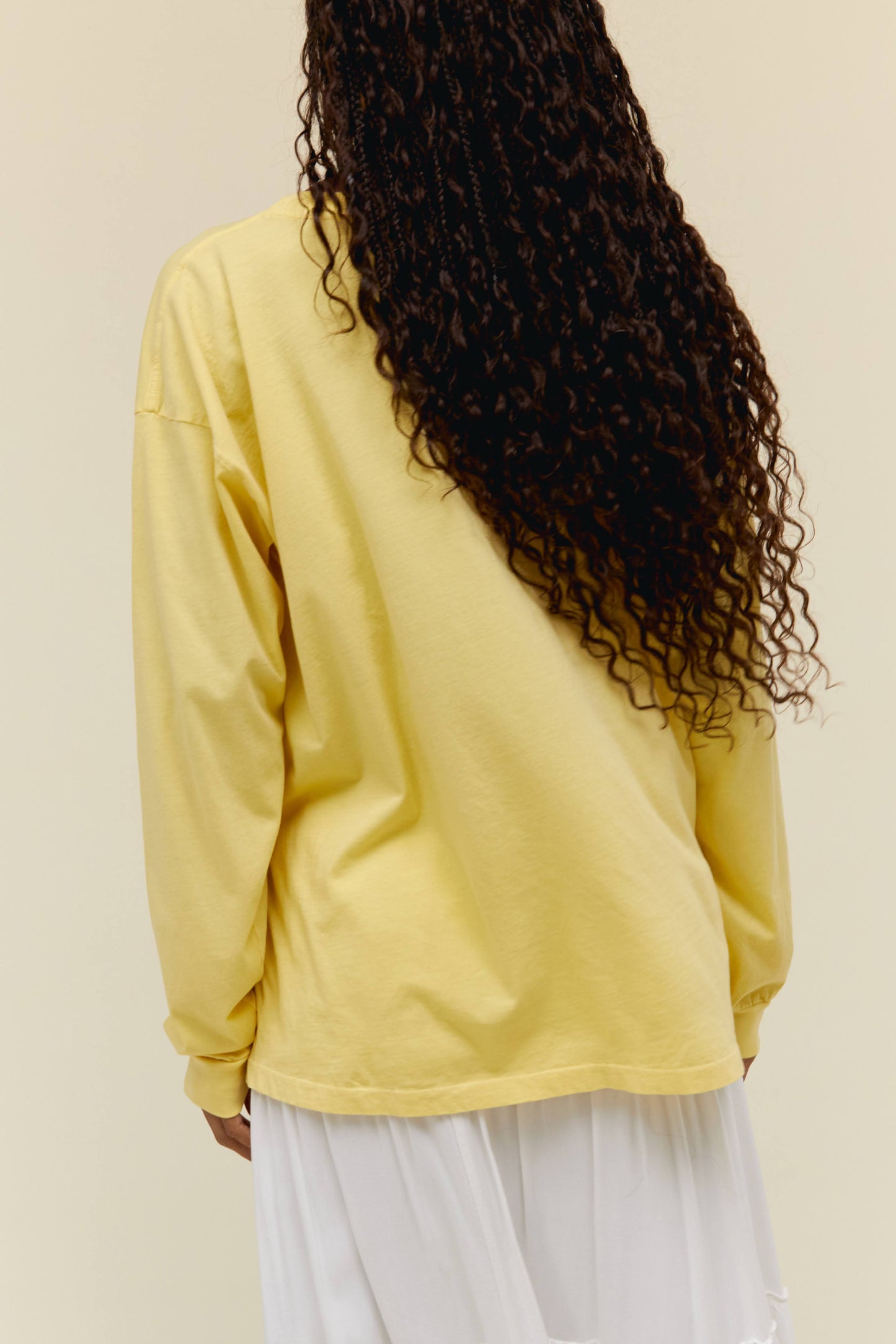 A model featuring a yellow long sleeve merch stamped with "Grateful Dead" in pink font and designed with a graphic of a surfing bear.