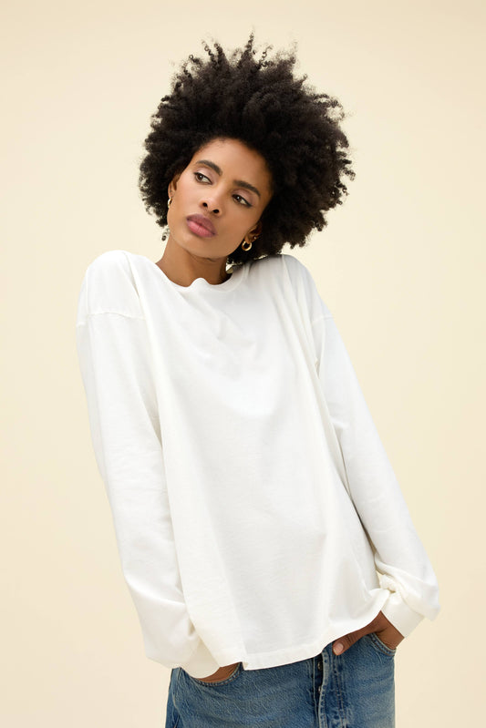A model featuring a long sleeve merch in vintage white.
