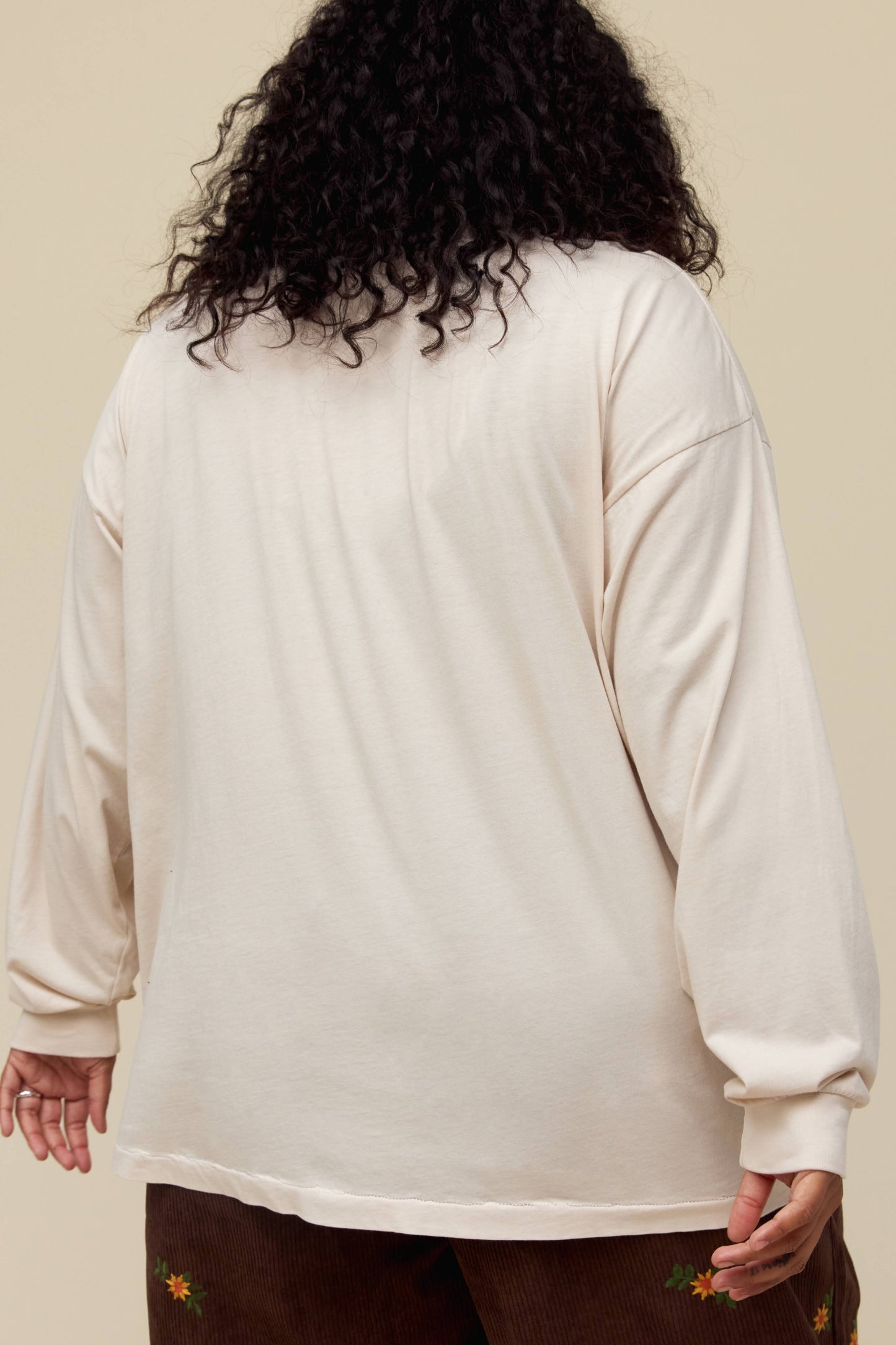 A model featuring a dirty white long sleeve designed with a king card and a portrait of Elvis stamped with his name.