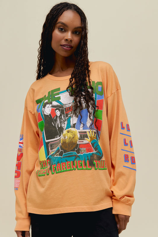A model featuring a peach long sleeve merch stamped with 'The Who' in green font and a graphic photo of the band