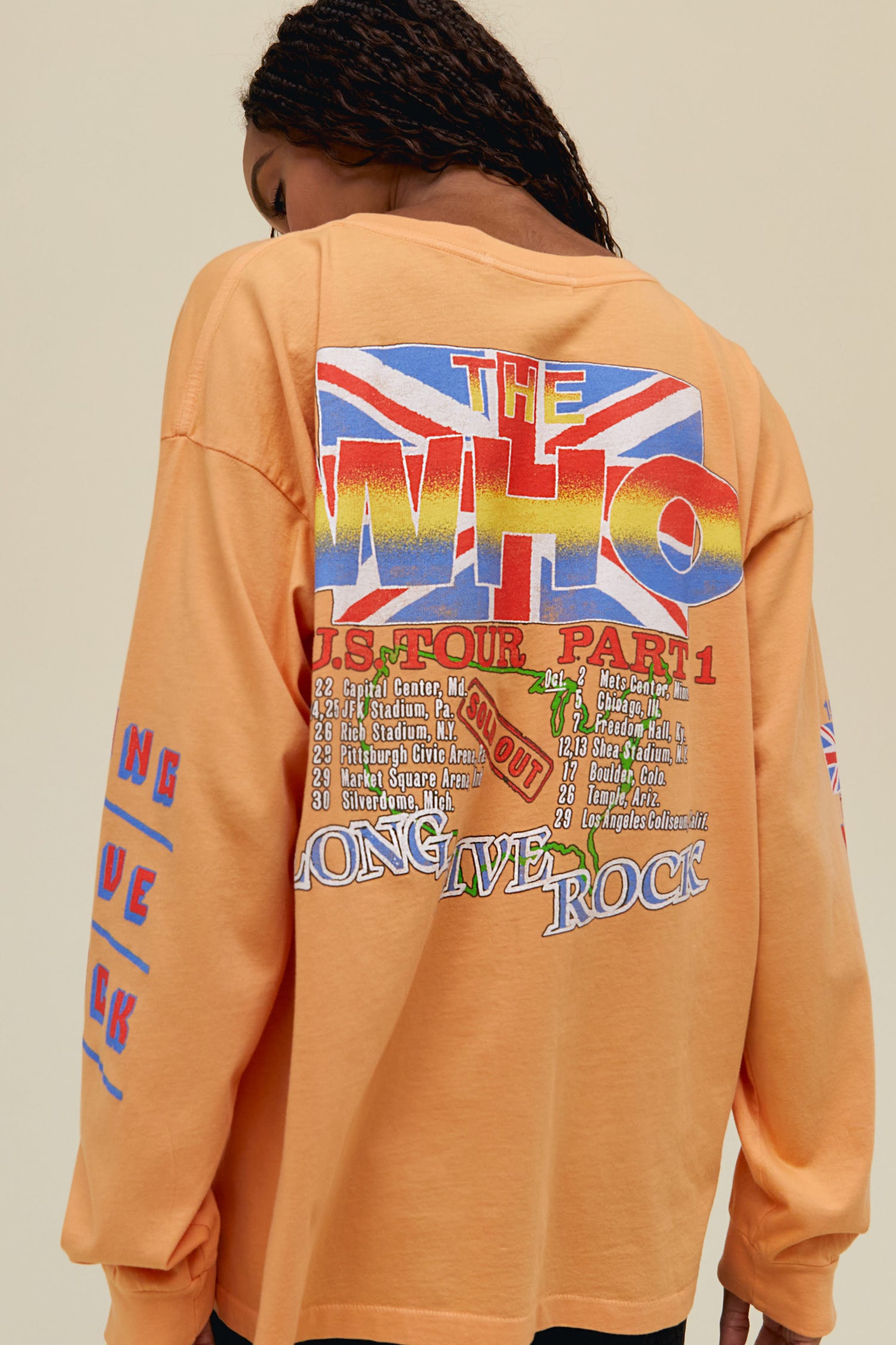 A model featuring a peach long sleeve merch stamped with 'The Who' in green font and a graphic photo of the band