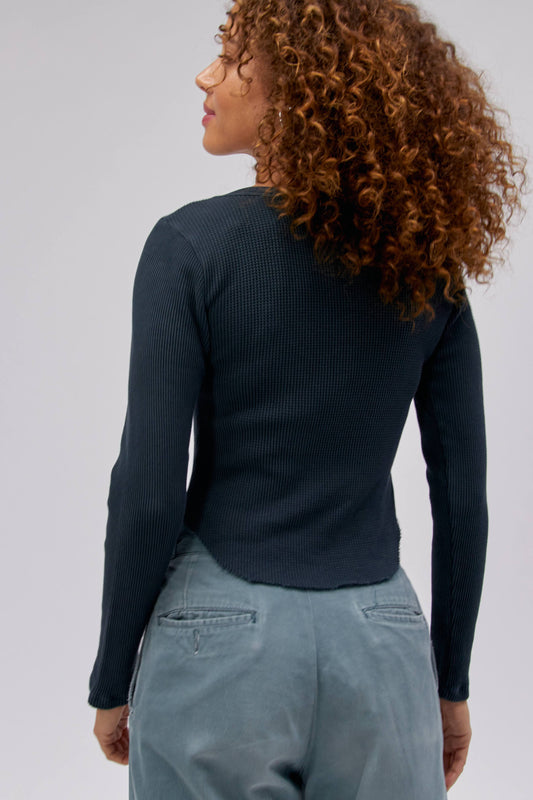 Curly haired model wearing a long sleeve thermal top with Tom Petty 'Damn The Torpedoes' graphic artwork.