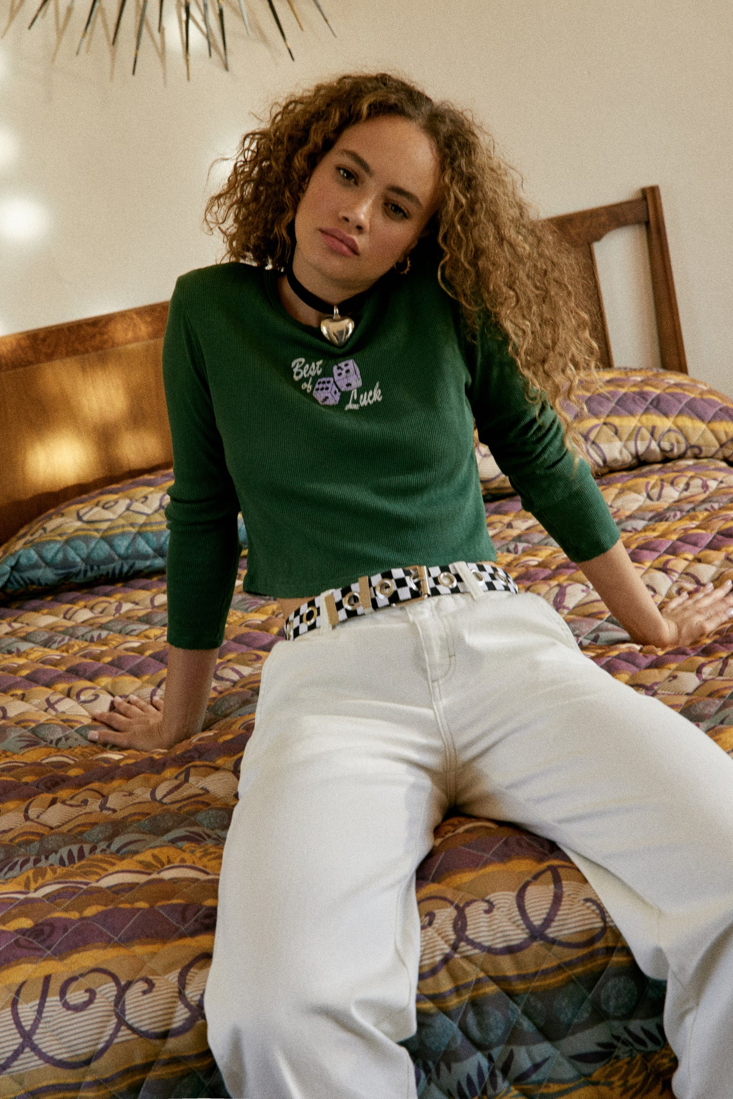 A curly-haired model featuring a storm geen pointelle long sleeve stamped with 'Best of Luck'.