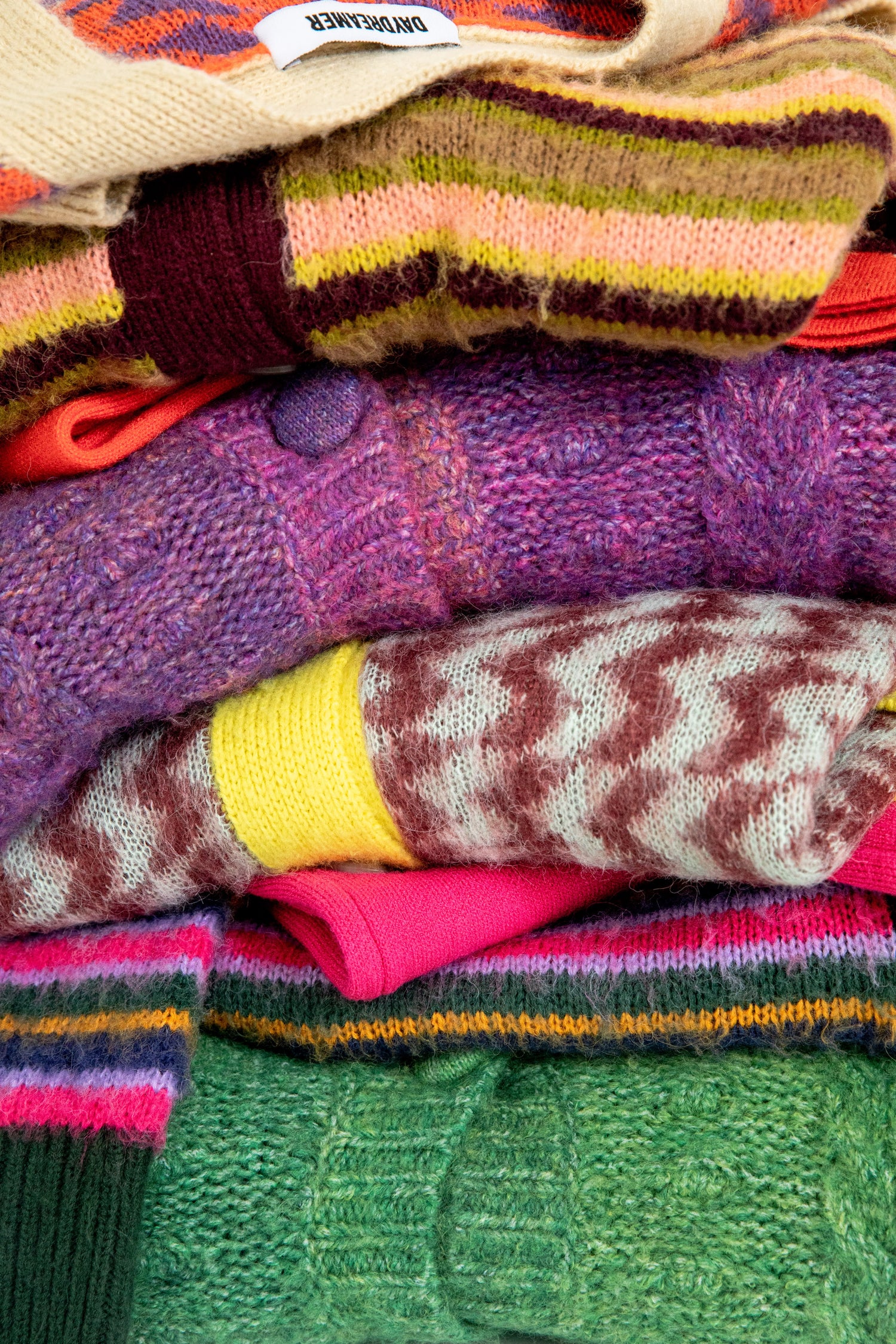 STACK OF MULTICOLORED AND PATTERNED KNITS AND SWEATERS