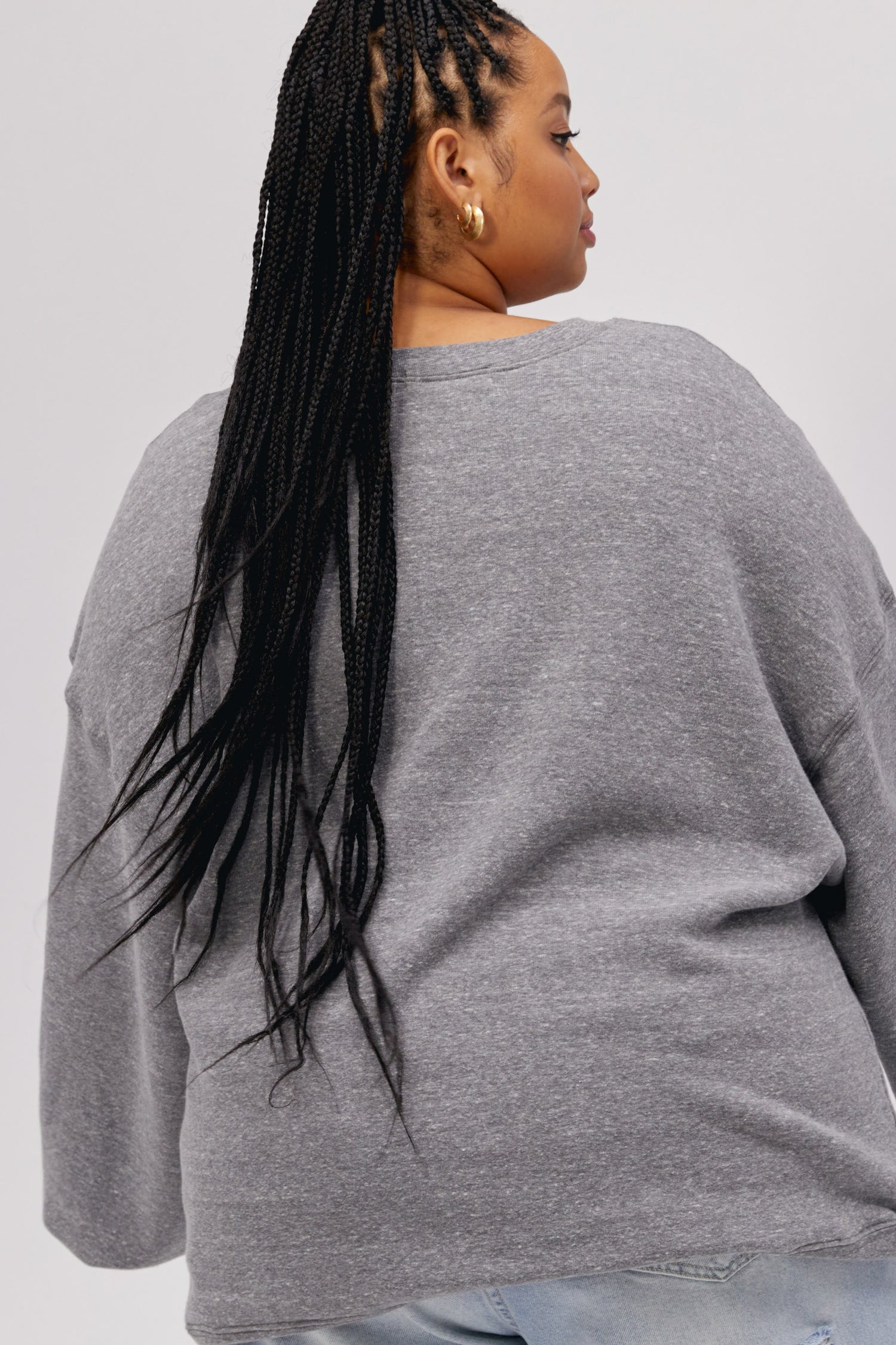 Plus size model wearing a grey crewneck sweatshirt with collegiate style 'New York' graphic lettering.