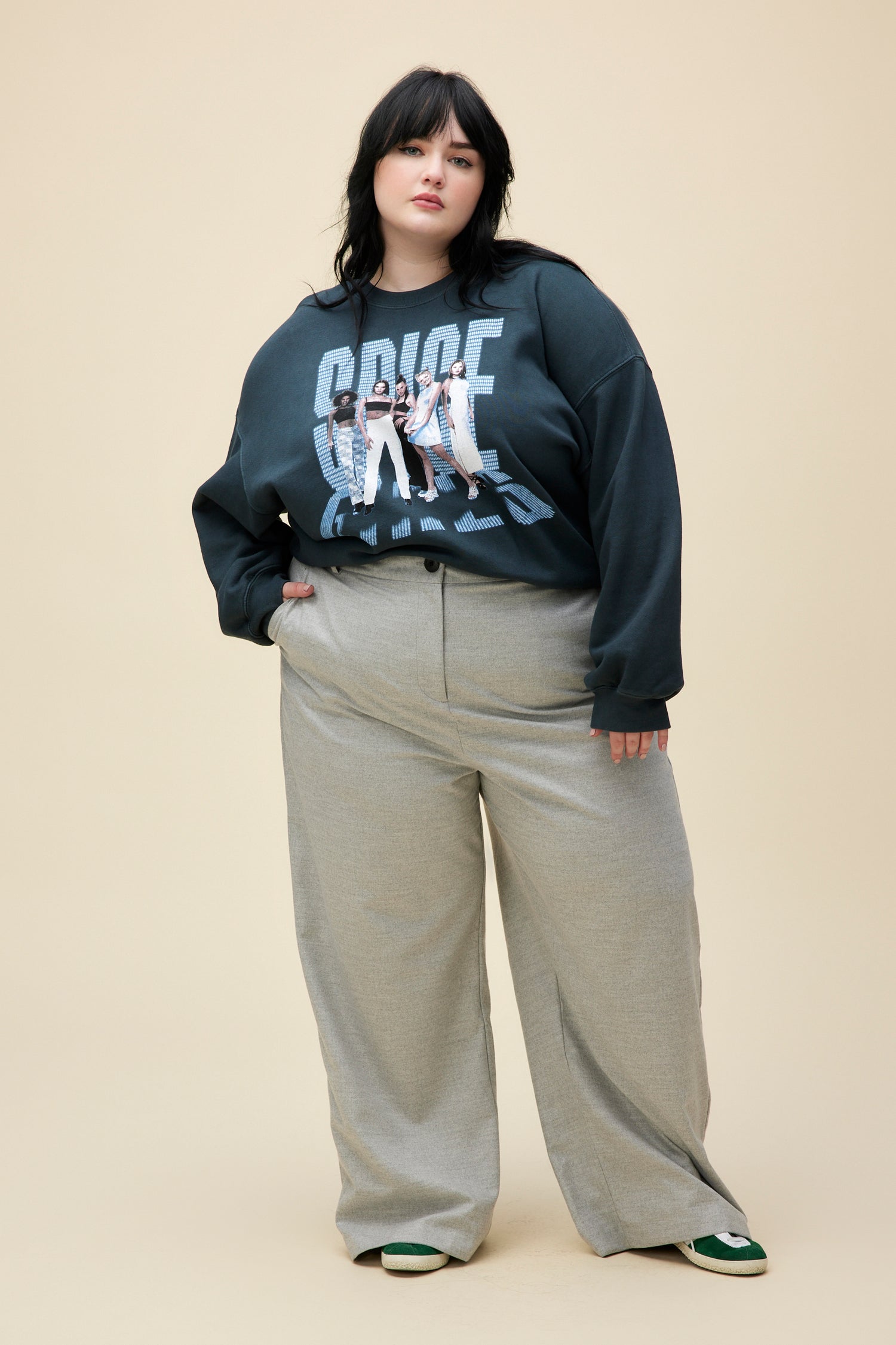 A  plus size model wearing black sweatshirt featuring a large font "SPICE GIRLS" and a portrait of the group. 