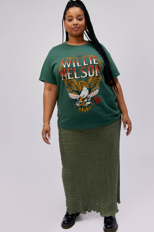 A dark-haired model featuring a green tee stamped with 'Willie Nelson/' and designed with a bird with 'Abott Texas' on its mouth.