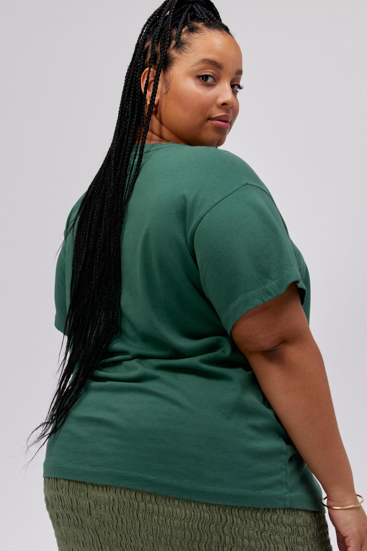 A dark-haired model featuring a green tee stamped with 'Willie Nelson' and designed with a bird with 'Abott Texas' on its mouth.