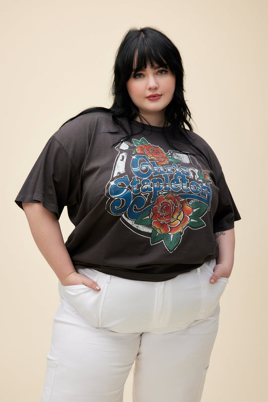 A plus size model featuring a black merch tee stamped with 'Chris Stapleton' in the middle with flowers around.