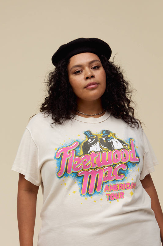 A model featuring a dirty white Fleetwood Mac es tour tee designed with with their group name and a penguin graphic; with a special shoutout to their American Tour featuring their city stops stamped on the back.
