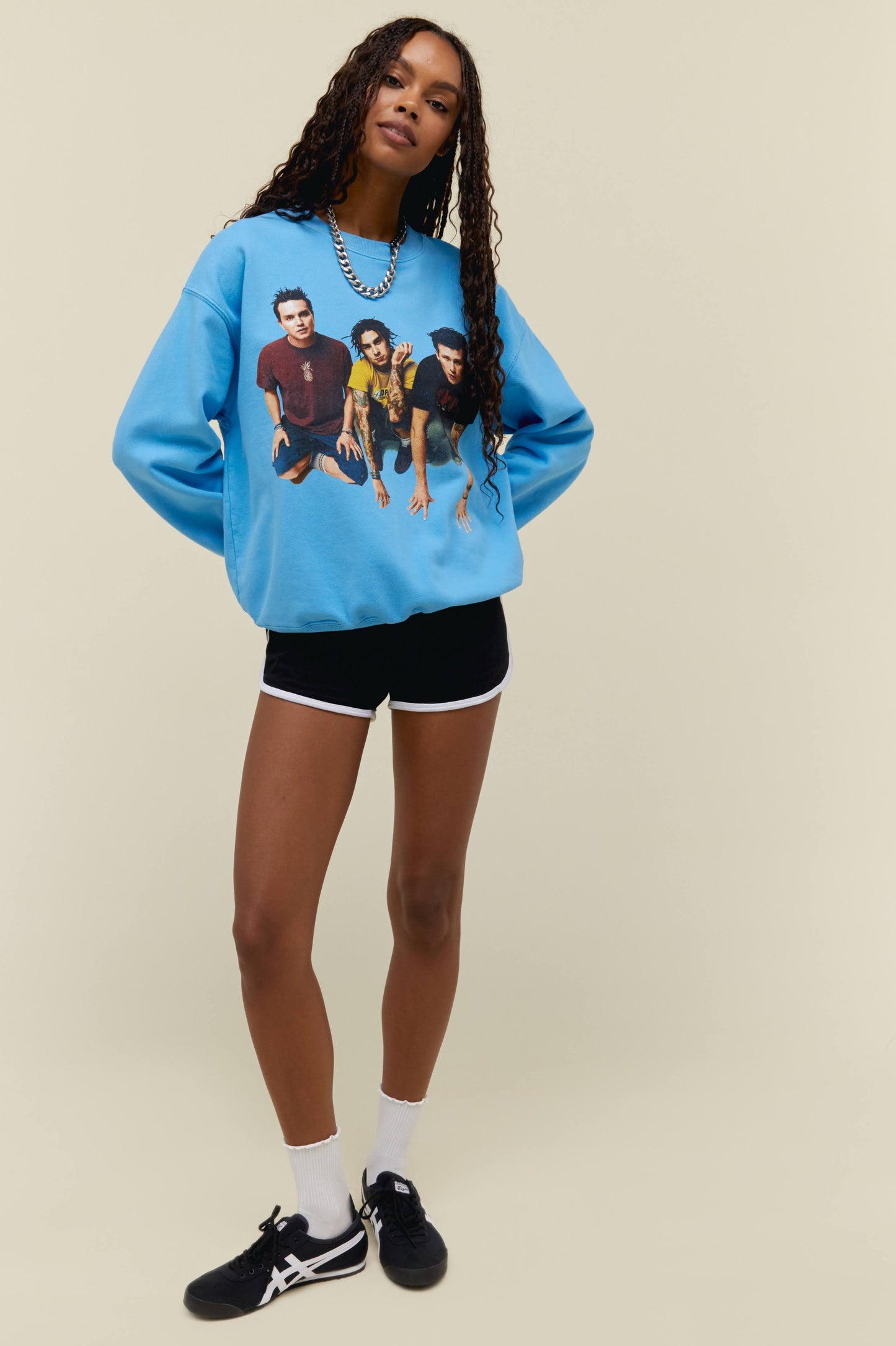 Model wearing a Blink 182 graphic sweatshirt in blue featuring portrait artwork and logo on back
