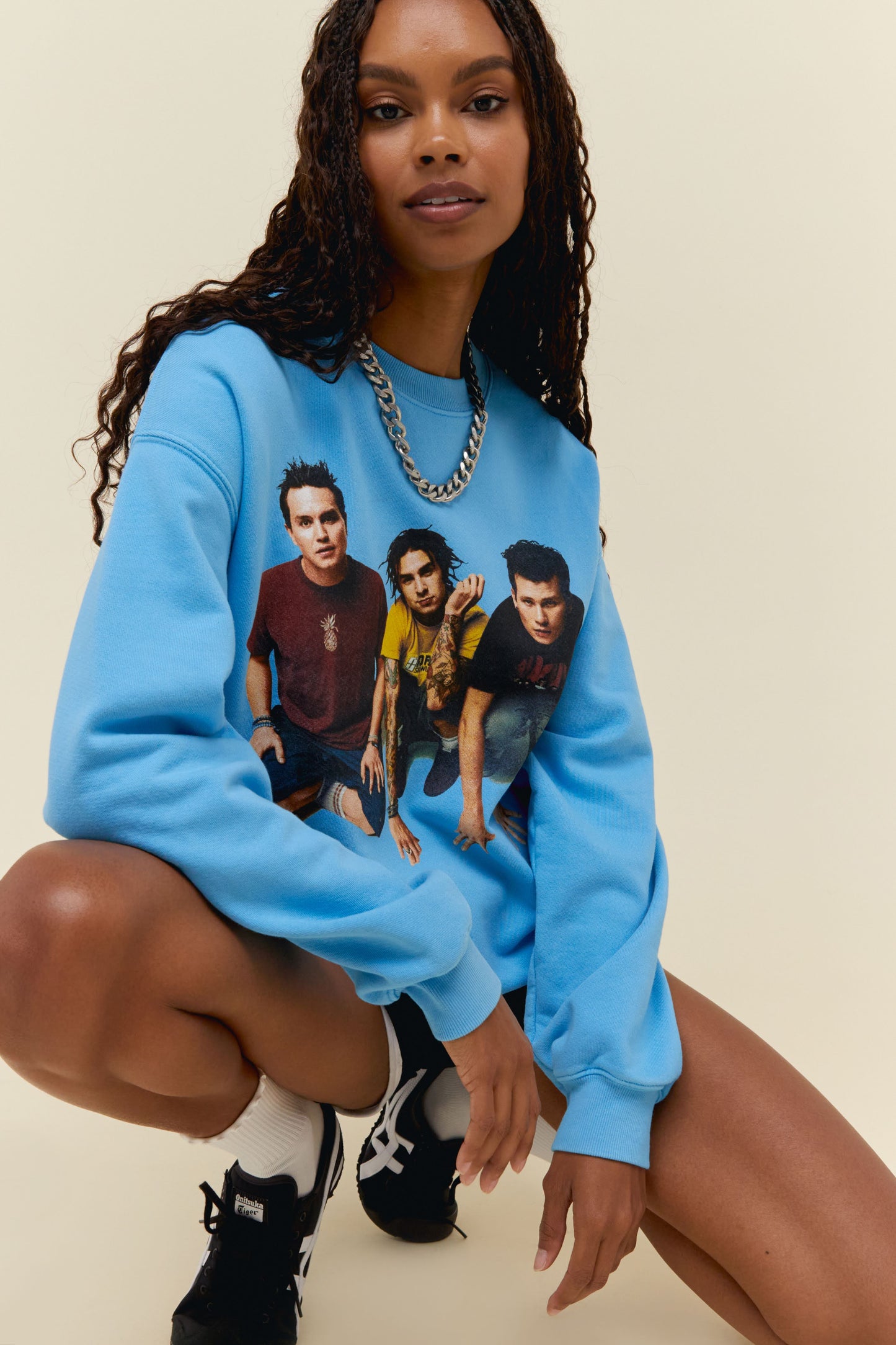 Model wearing a Blink 182 graphic sweatshirt in blue featuring portrait artwork and logo on back