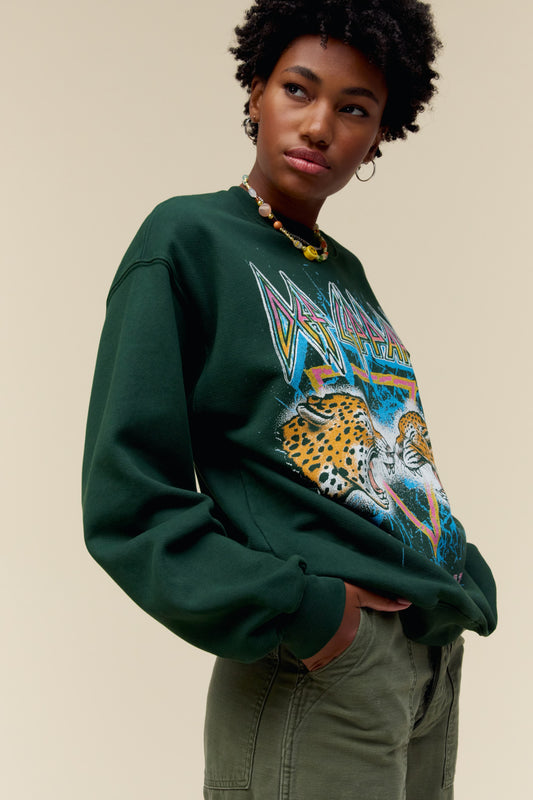 A model featuring a vintage green bf crew stamped with Def Leppard and a graphic of two leopards facing each other in the middle.