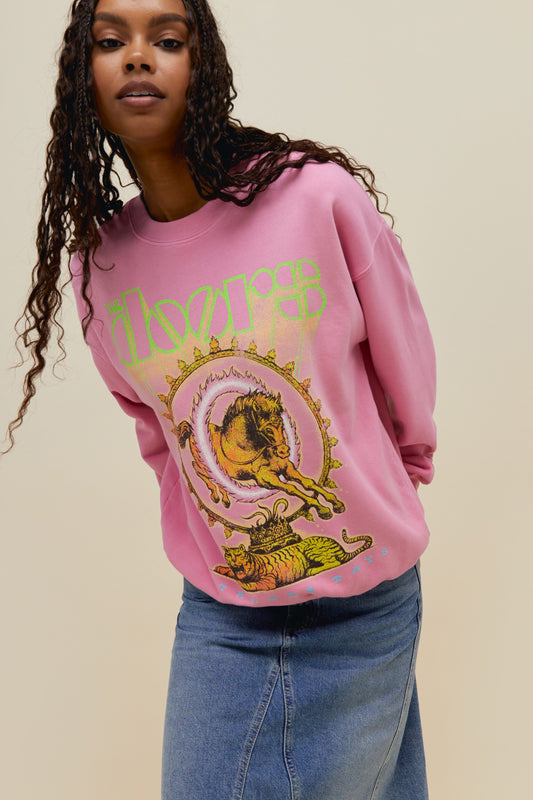 A dark-haired model featuring a pink sweatshirt with a large "THE DOORS" font on top and an exclusive rendition of The Door's Full Circle Album Art 