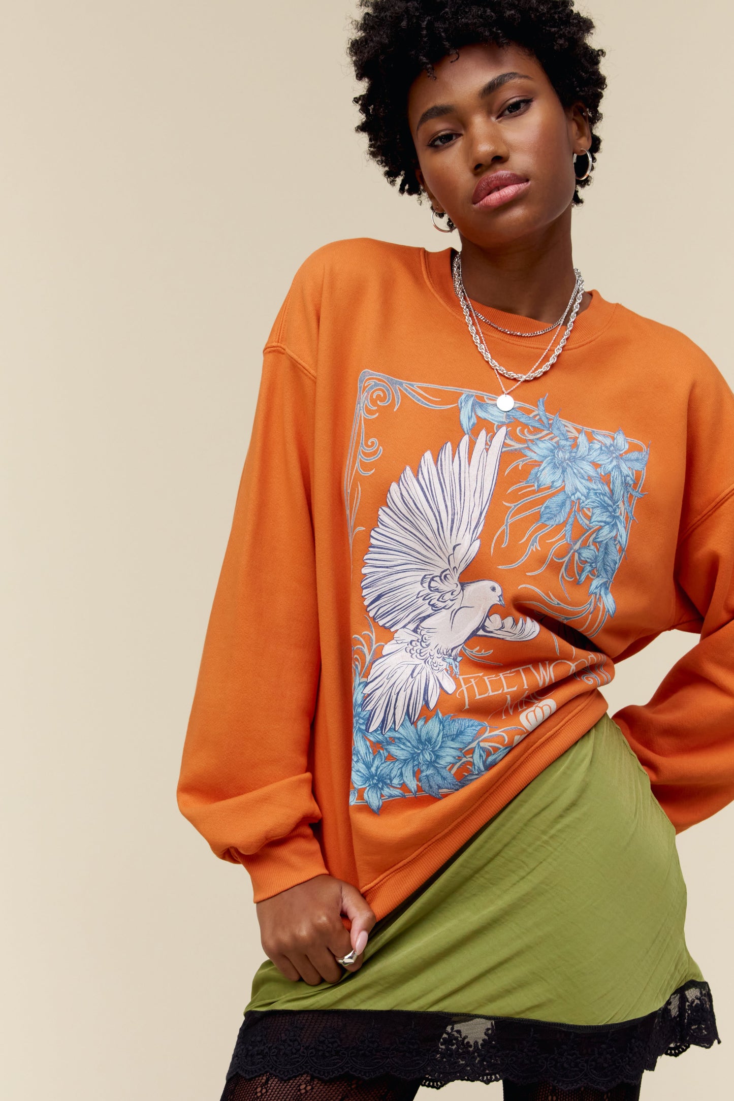 A model featuring a tangerine long sleeve designed with dove artwork - a symbol that’s become synonymous with the crew.