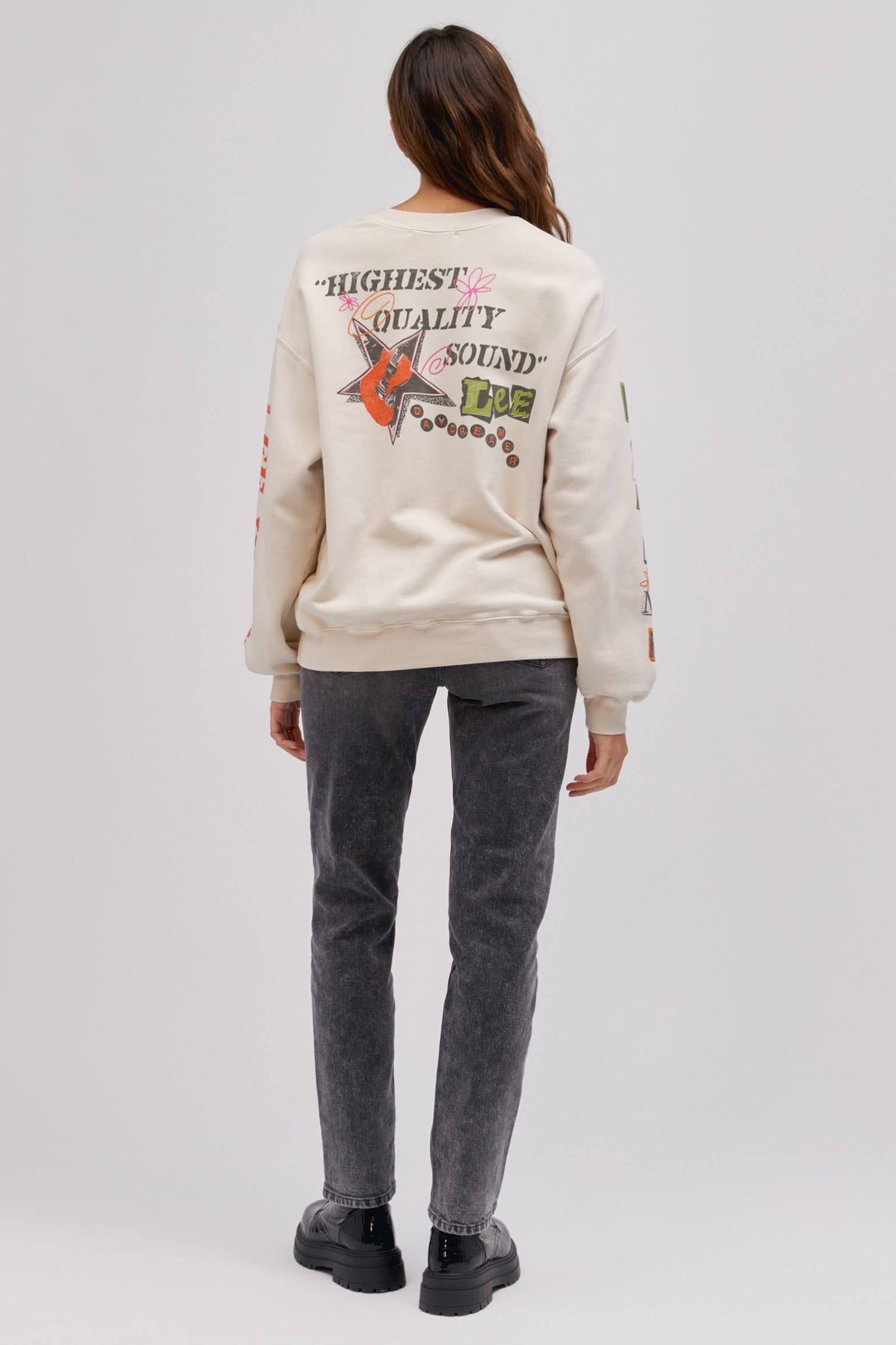 backside of model in standing pose wearing graphic sweatshirt and washed denim jeans