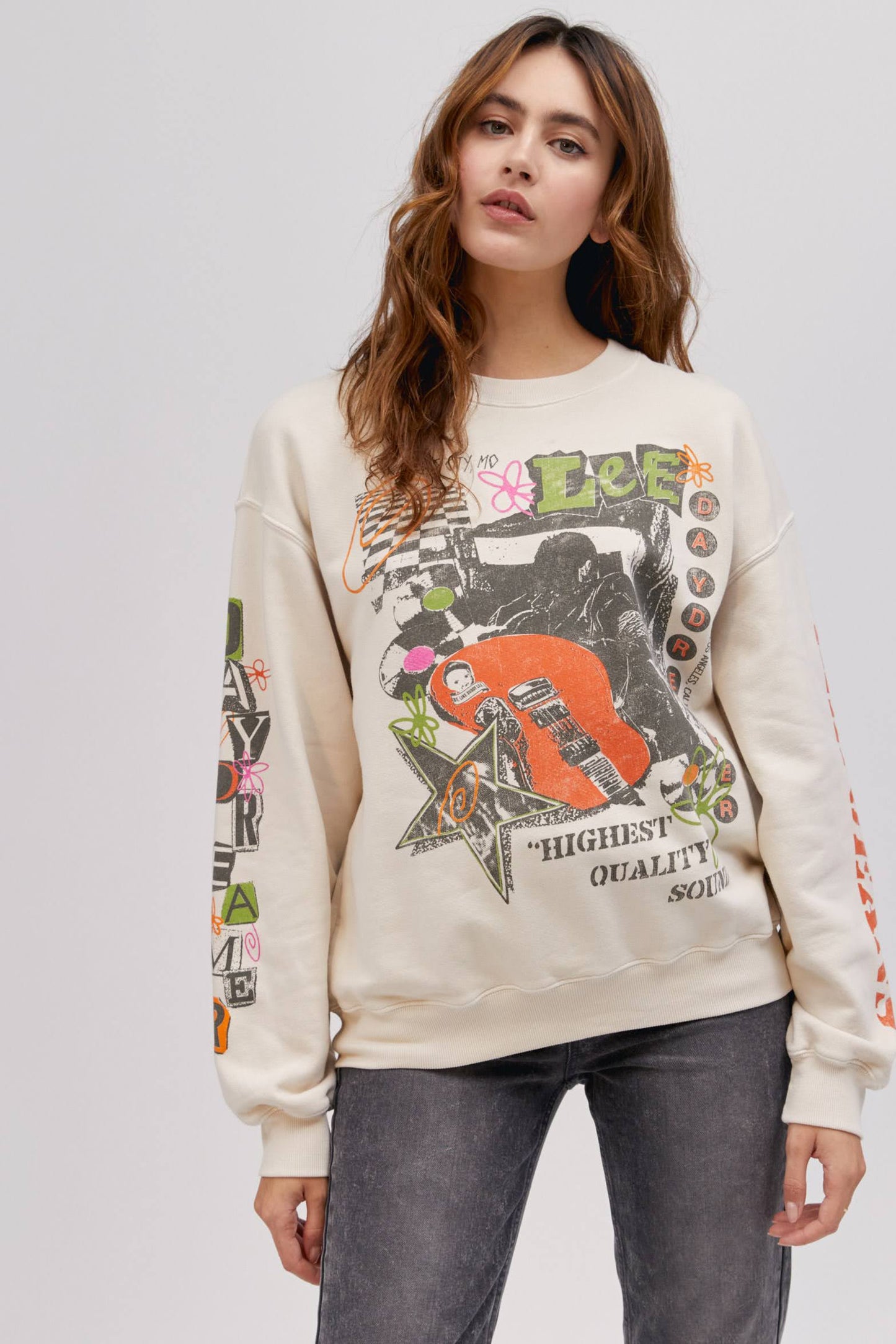 long haired model wearing off white colored sweatshirt with washed graphics