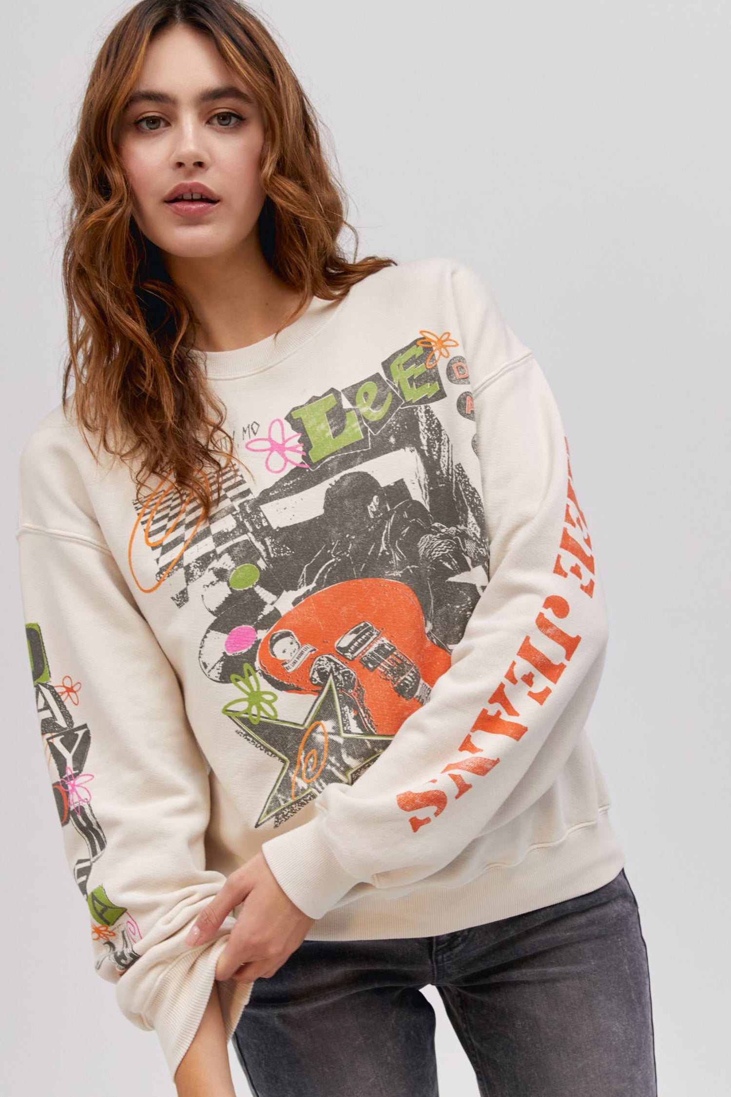 long haired model posing and wearing an off white colored sweatshirt with washed graphics