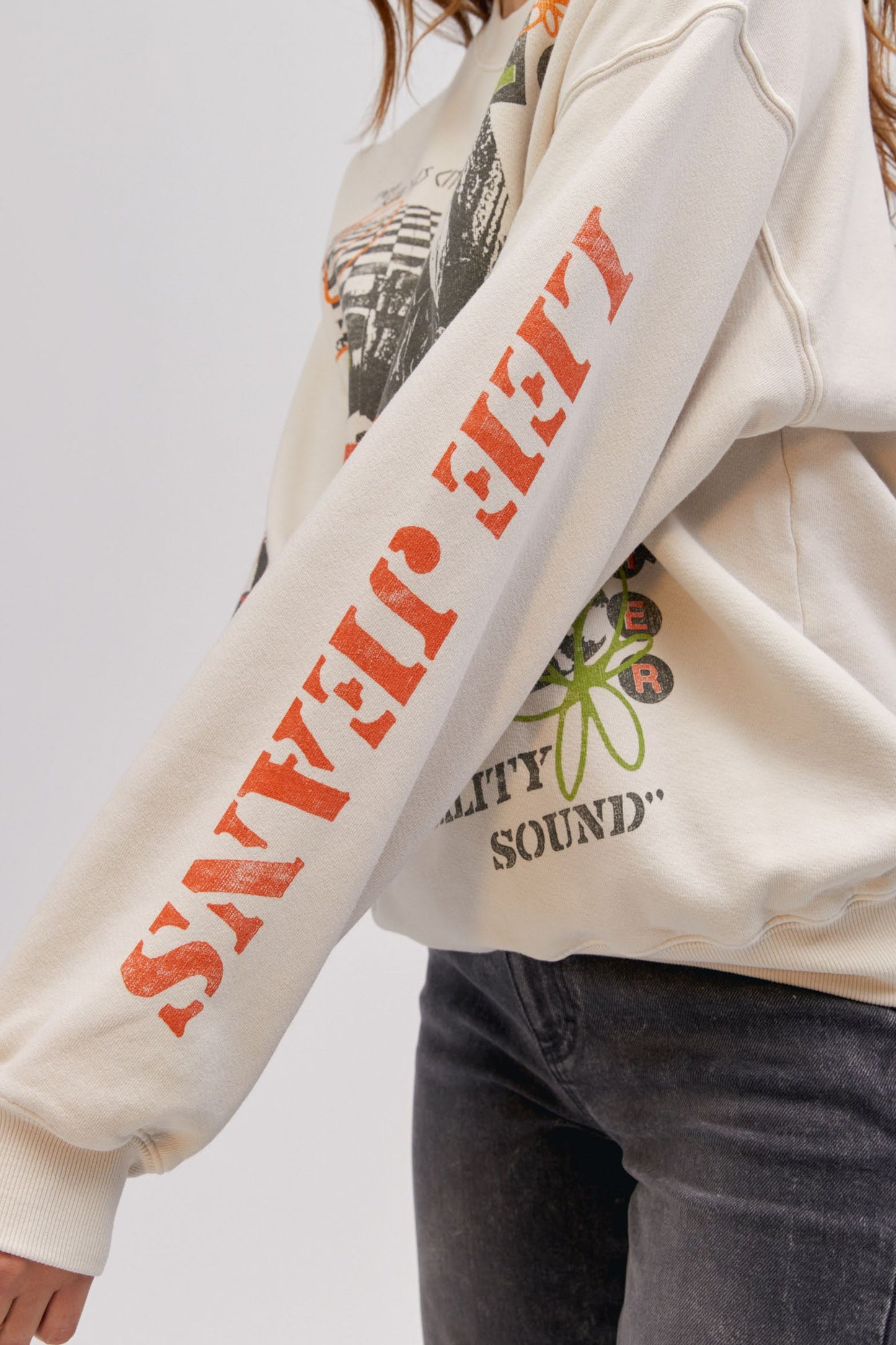 close up photo of model wearing off white colored sweatshirt with brand logo graphics on the sleeve