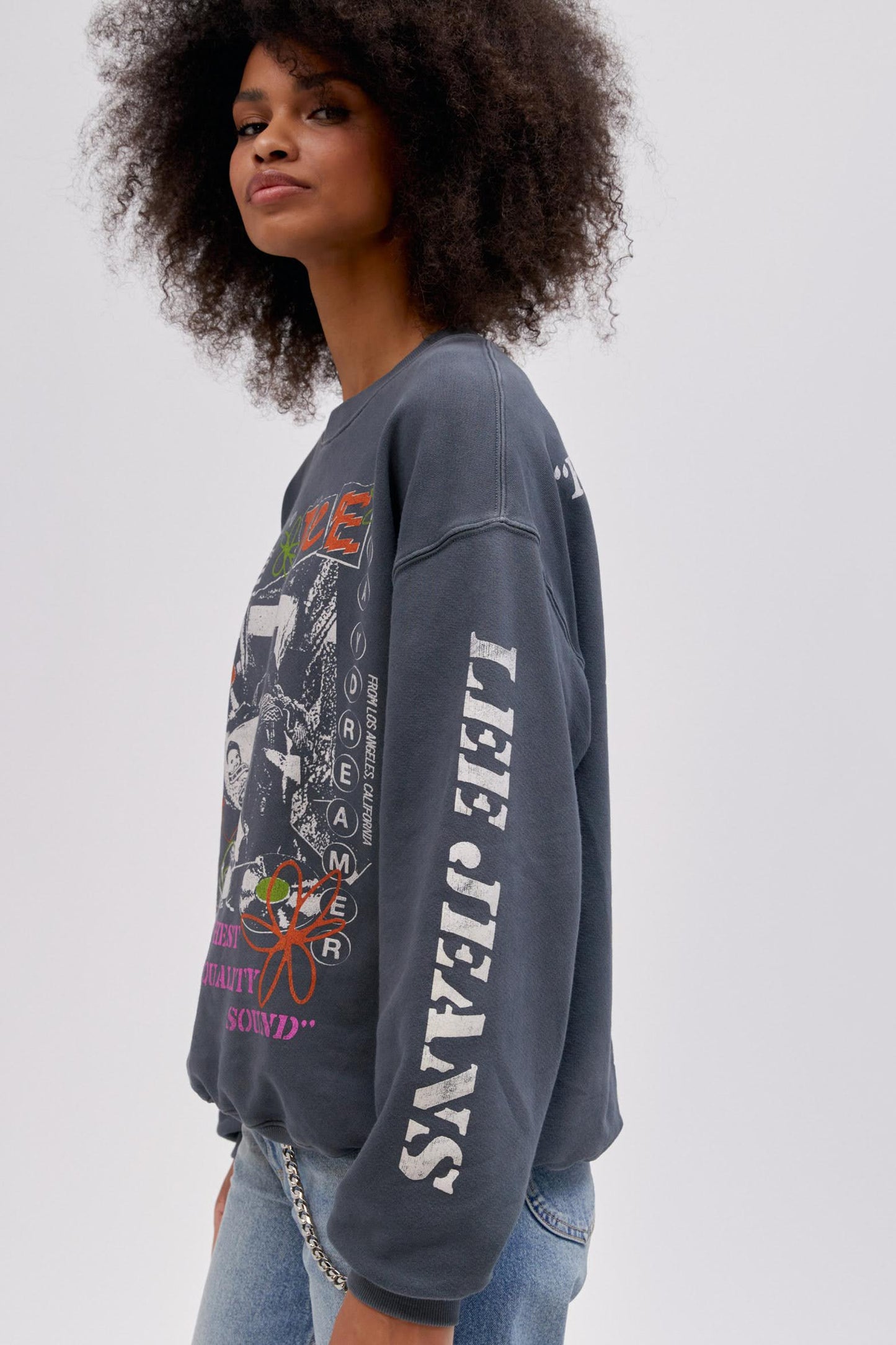 Side profile curly haired model wearing a Lee x Daydreamer collab graphic sweatshirt in washed black.
