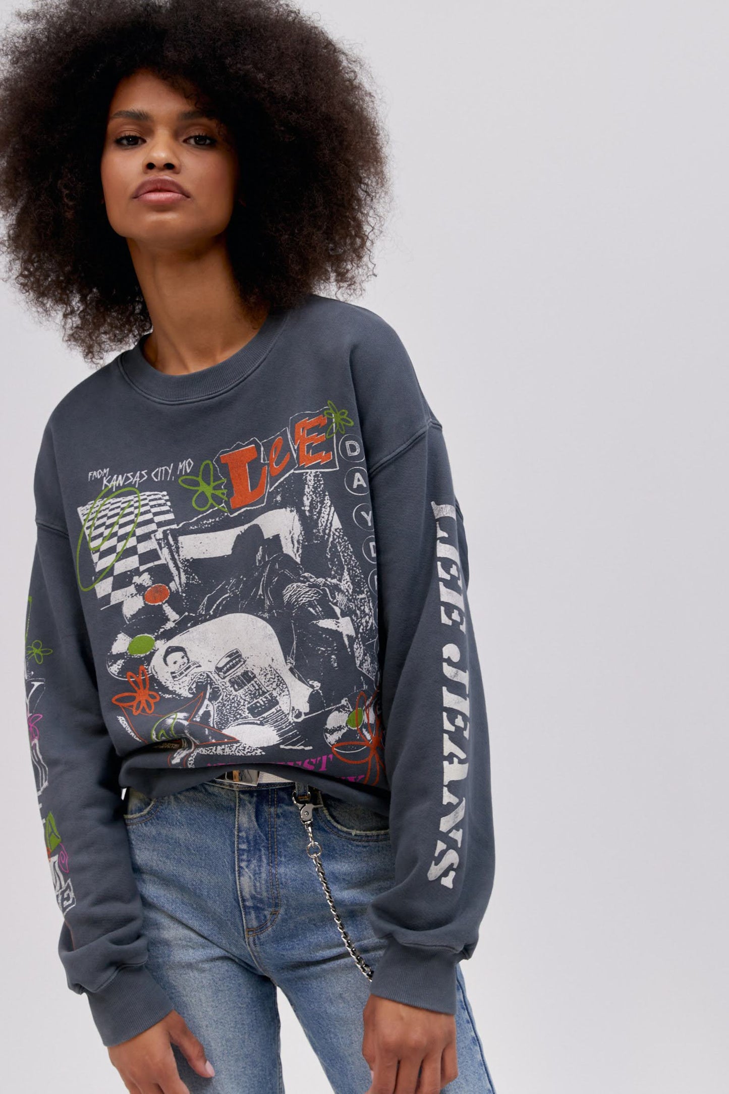 Curly haired model wearing a Lee x Daydreamer collab graphic sweatshirt in washed black.