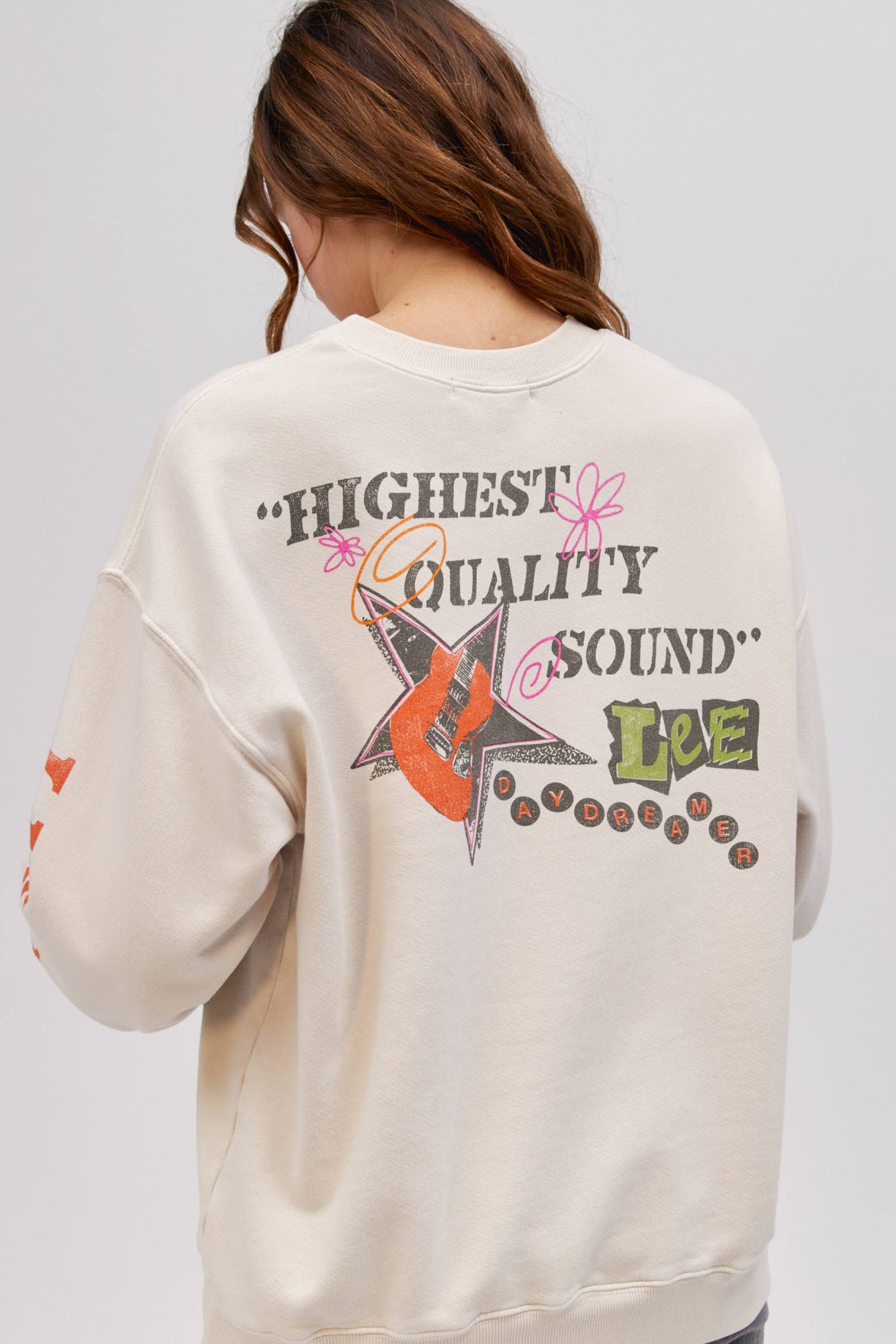backside of model wearing an off white colored sweatshirt with graphic designs