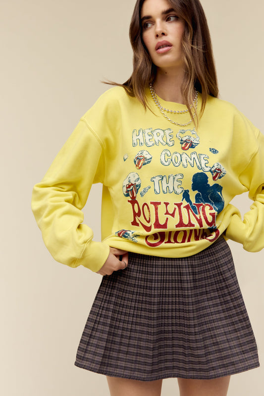 A model featuring a yellow cream bf crew stamped with "Here Comes The Rolling Stones" in white and red font, and a silhouette of a man singing.