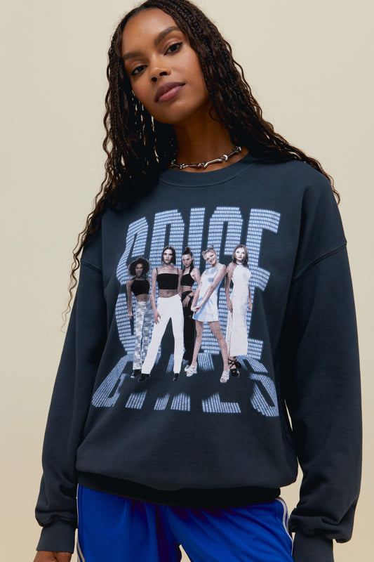 A  dark-haired model wearing black sweatshirt featuring a large font "SPICE GIRLS" and a portrait of the group. 