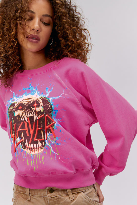 Model wearing Slayer graphic sweatshirt in pink with lightning artwork.