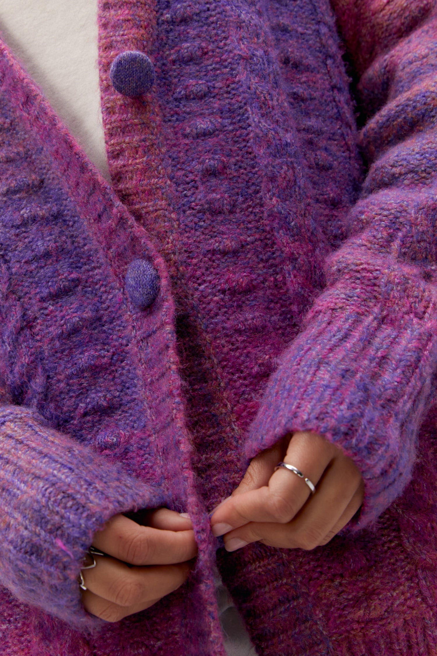 A curly-haired model featuring an ombre cardigan in Wild Orchid.
