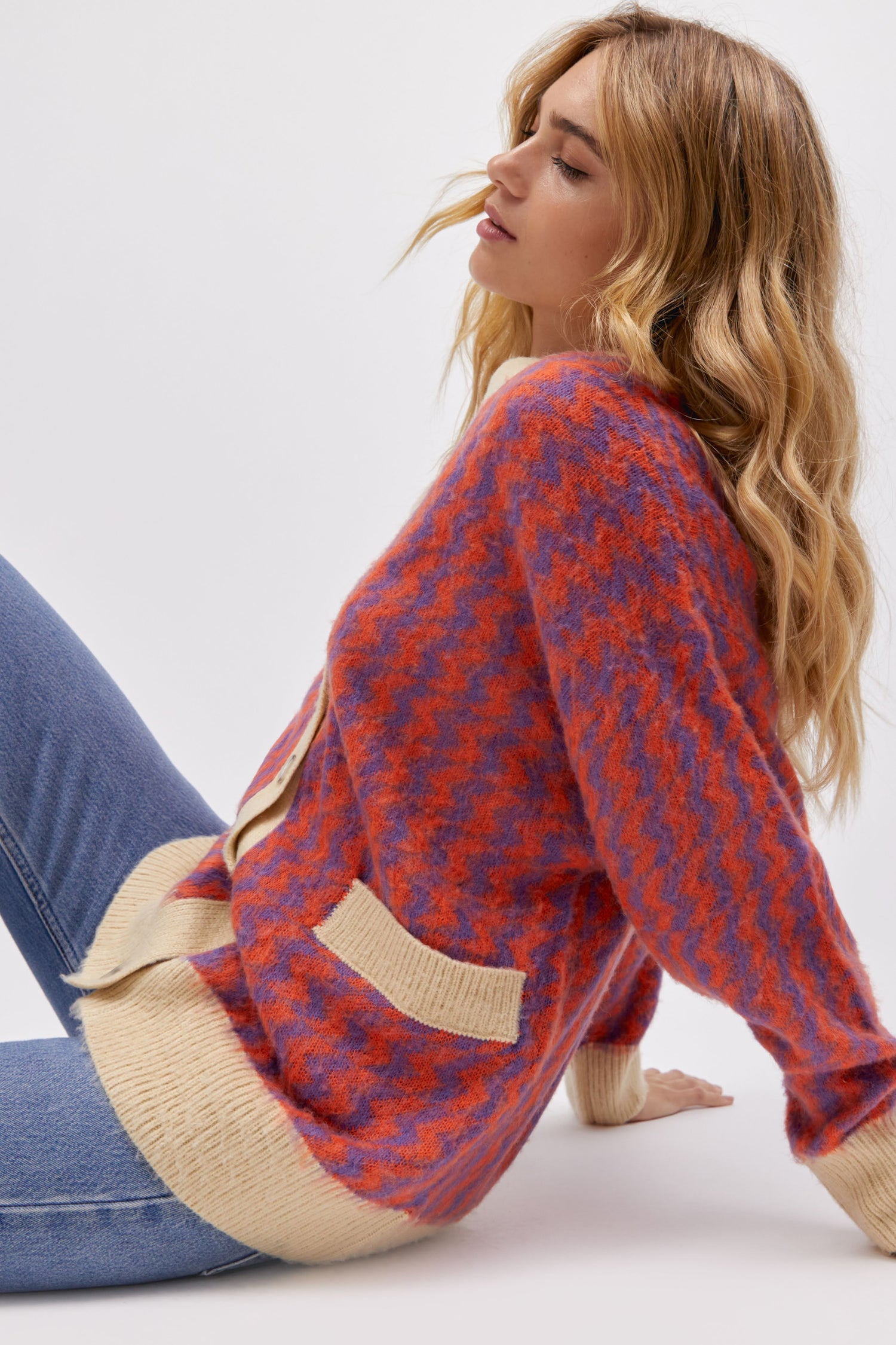 A blonde-haired model featuring a violet orange zig zag cardigan.