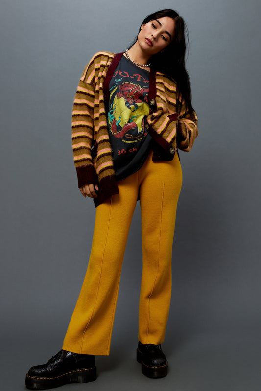 Model wearing a cherry crush striped cardigan styled with a Wu-Tang dragon graphic tee and gold knit pintuck pants