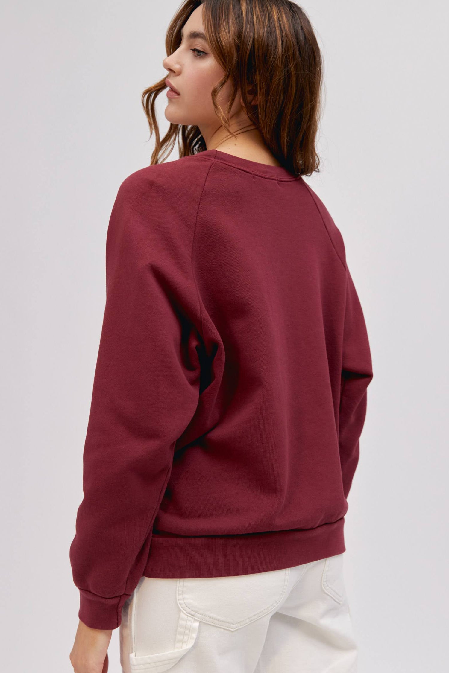 backside of long wavy haired model wearing maroon colored sweatshirt
