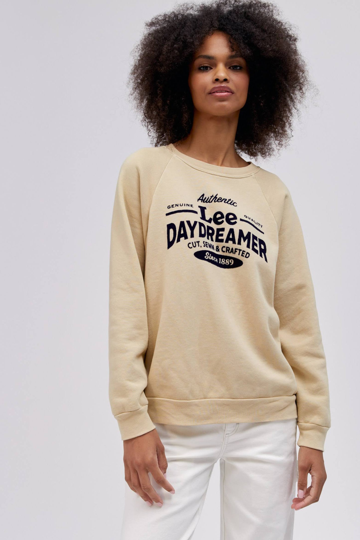curly haired model wearing a khaki colored sweatshirt
