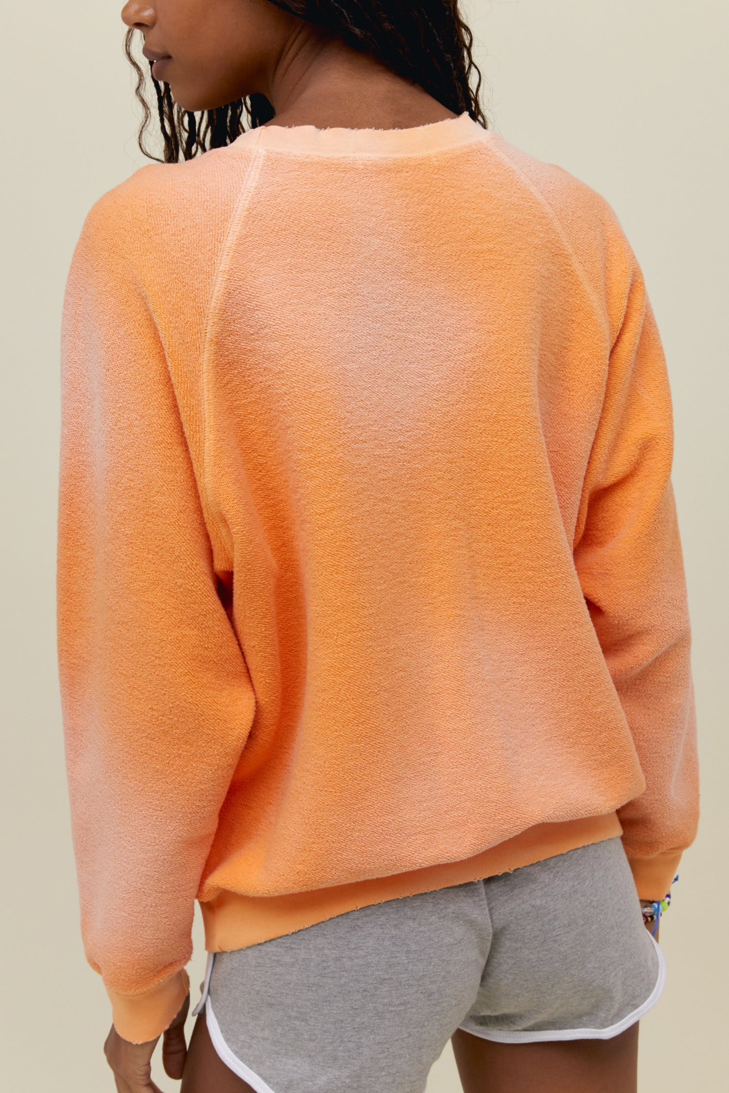 A model featuring a soft peach raglan crew stamped with "Pegasus Aviation Flight School" and a graphic of a pegasus on the center.