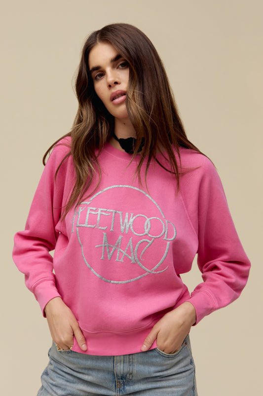 A model featuring a pink raglan crew stamped with Fleetwood Mac in a circle.