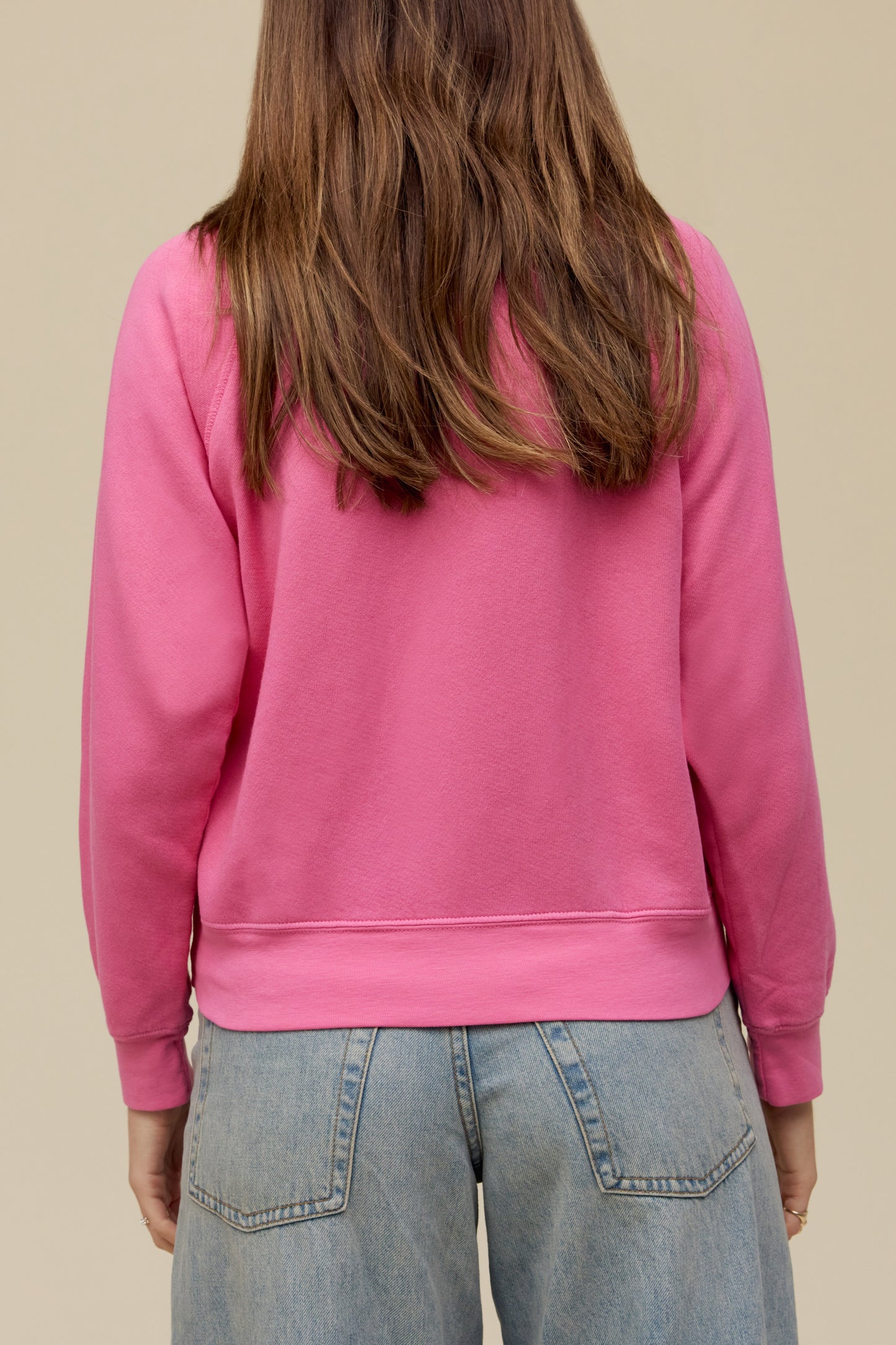 A model featuring a pink raglan crew stamped with Fleetwood Mac in a circle.