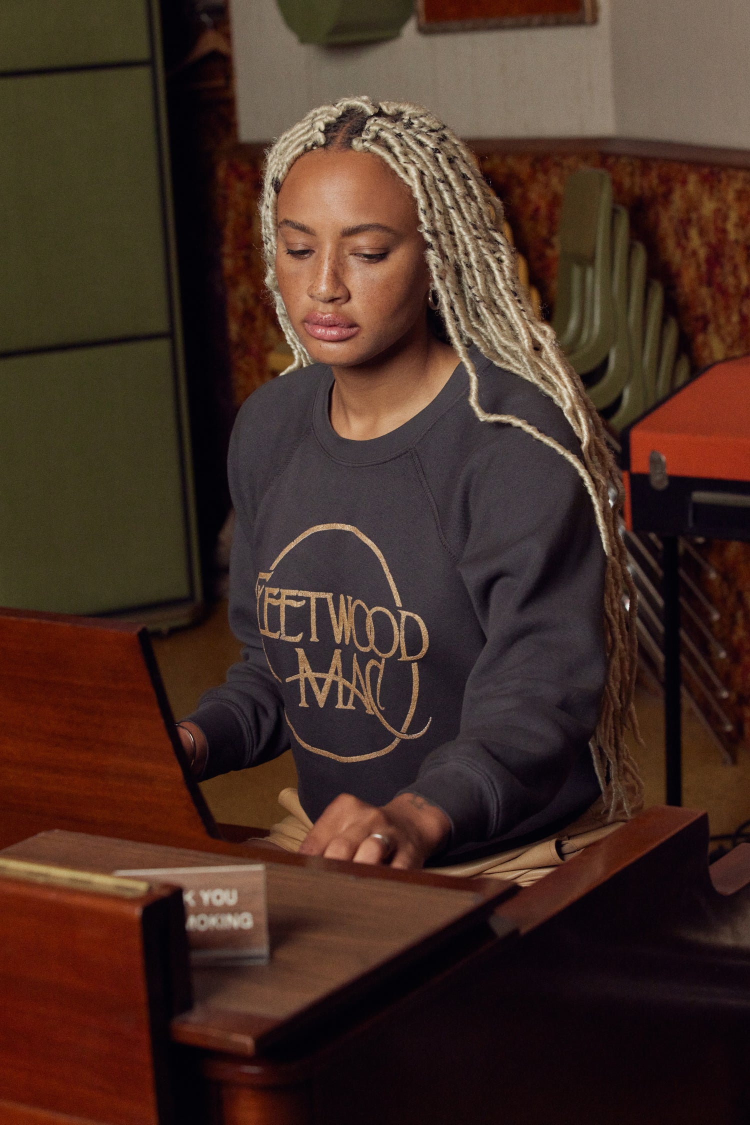 A model featuring a washed black raglan crew stamped with Fleetwood Mac in a circle.