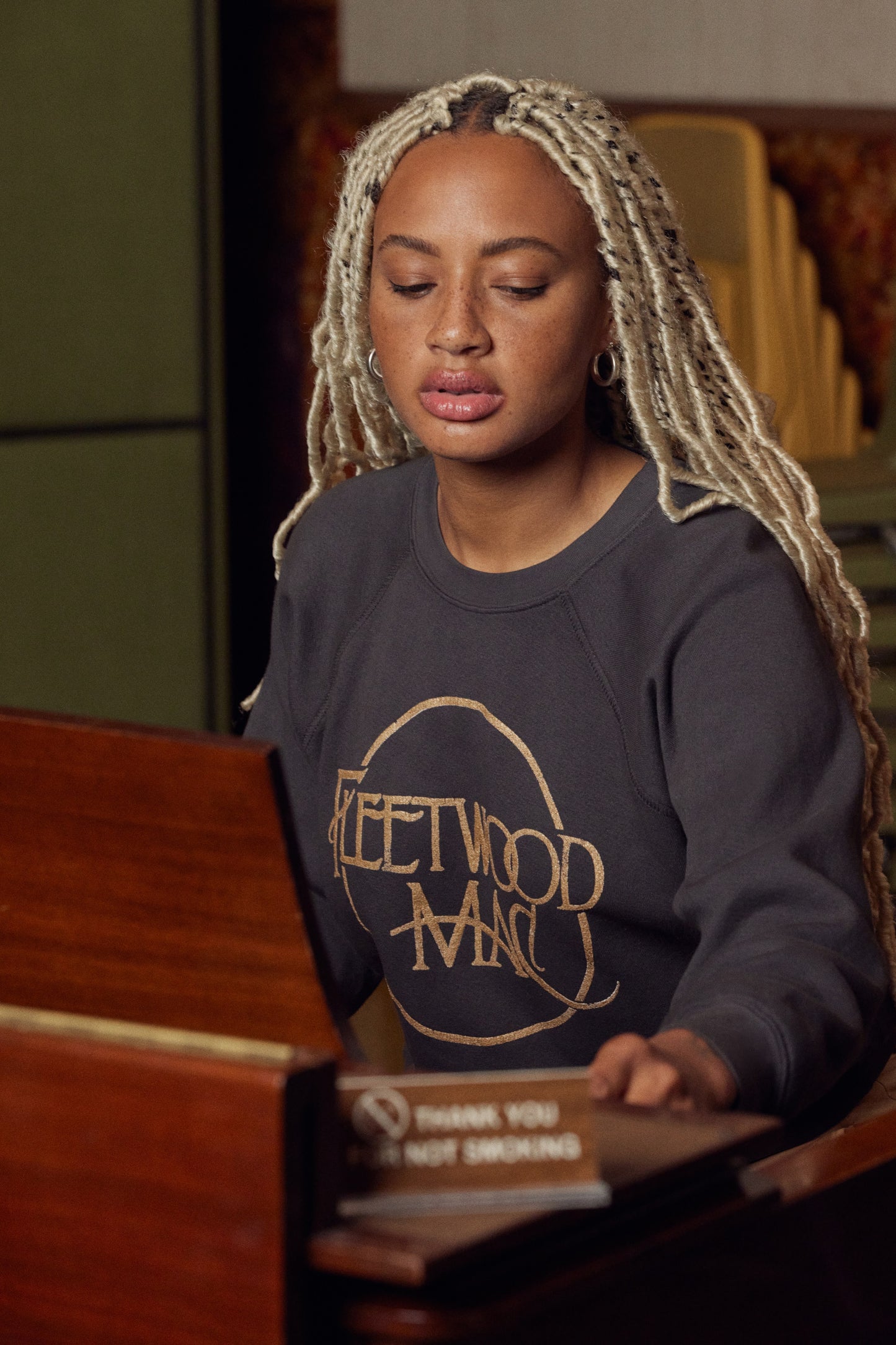 A model featuring a washed black raglan crew stamped with Fleetwood Mac in a circle.