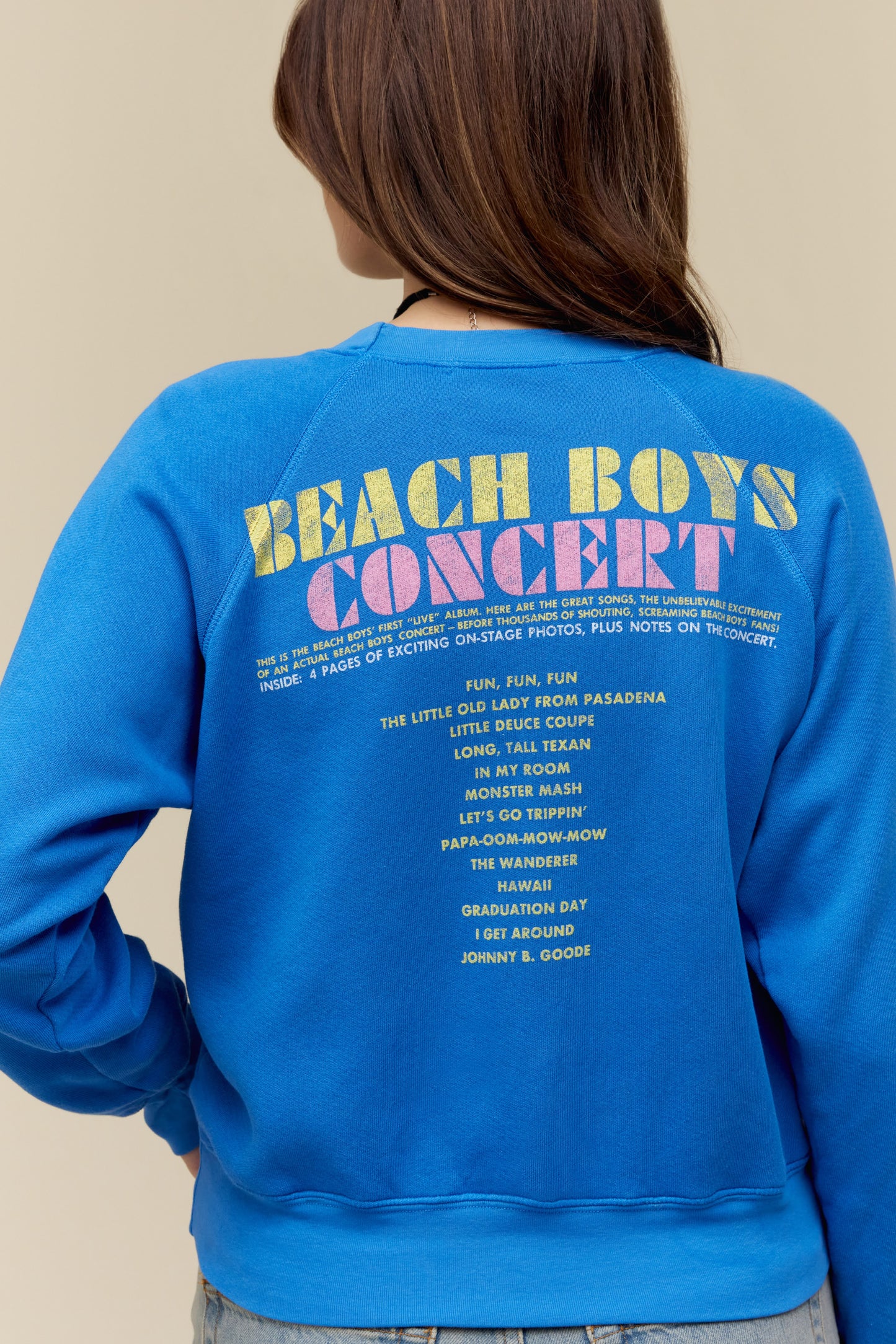 A model featuring a cobalt long sleeve designed with the band's group photo and stamped with the band's name.