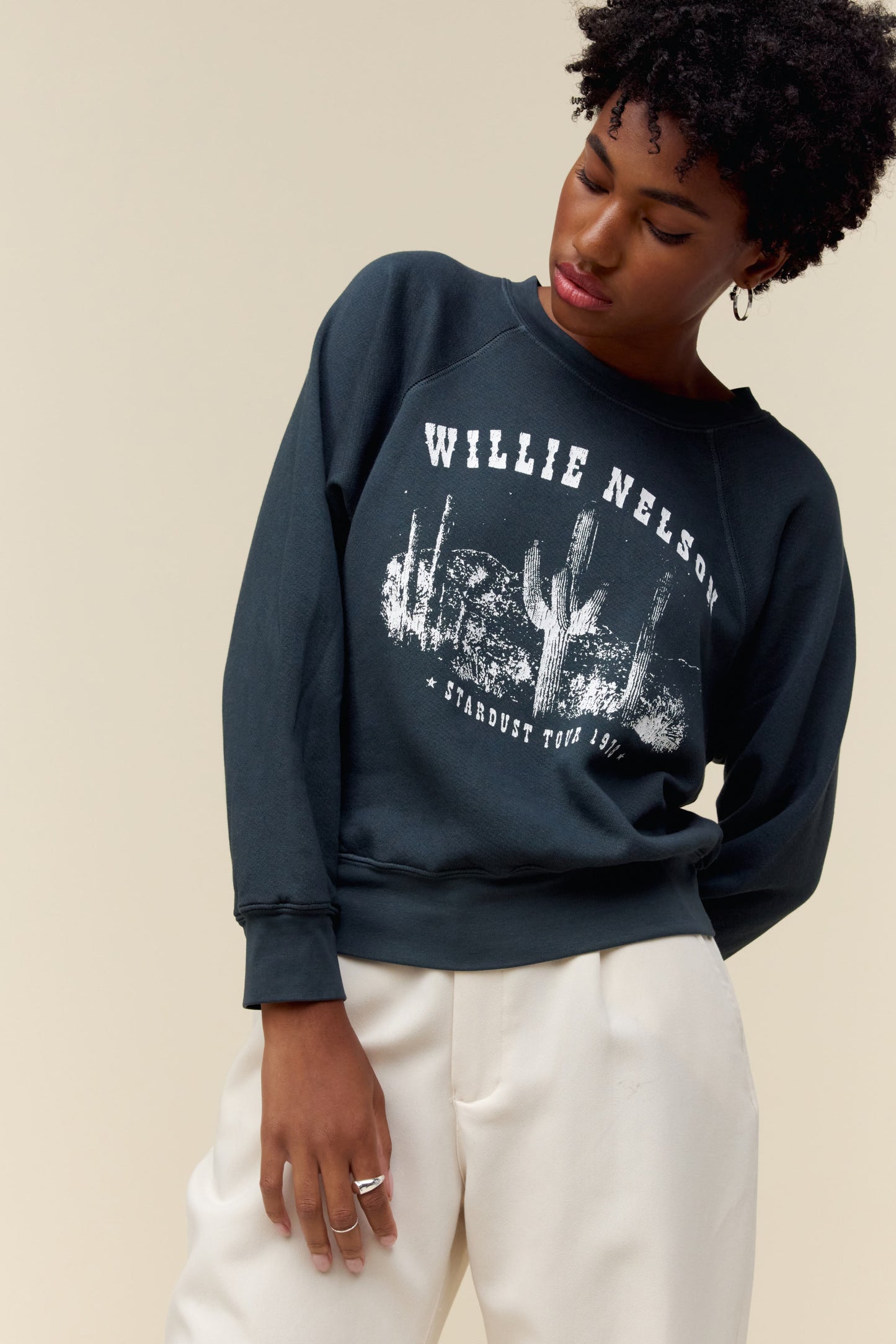 A model featuring a vintage black long sleeve stamped with Willie Nelson in white large font.