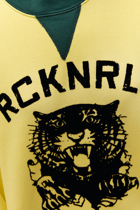 A model featuring a yellow long sleeve stamped with rcknrll, ddla in black large font and a tiger on the center.