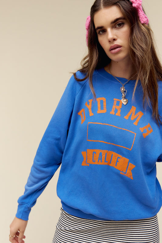 A model featuring a cobalt vintage sweatshirt stamped with DYDRMR, Calif and treated with a proprietary potassium spray giving each piece a special sun-faded effect. 