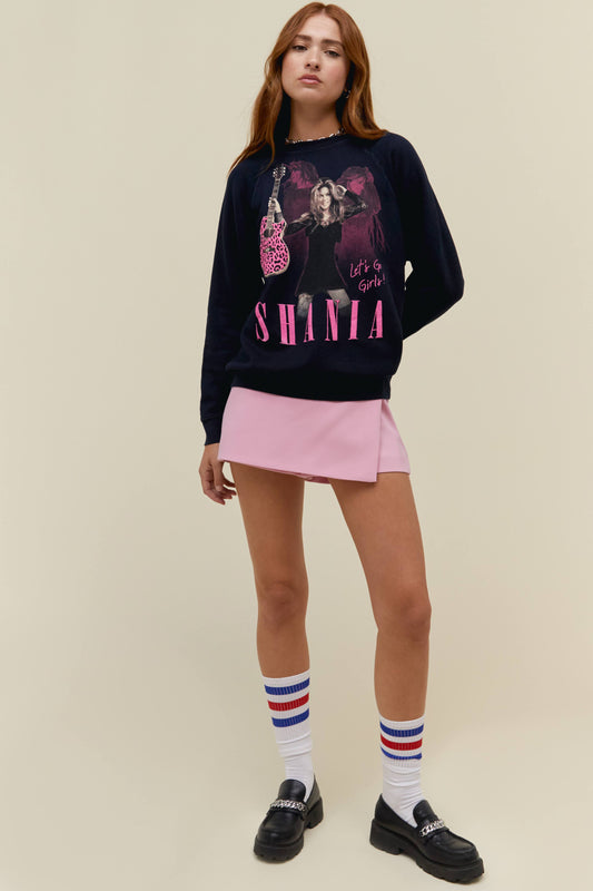A model featuring a black sweatshirt stamped with "SHANIA" and a portrait of the artist holding a guitar.