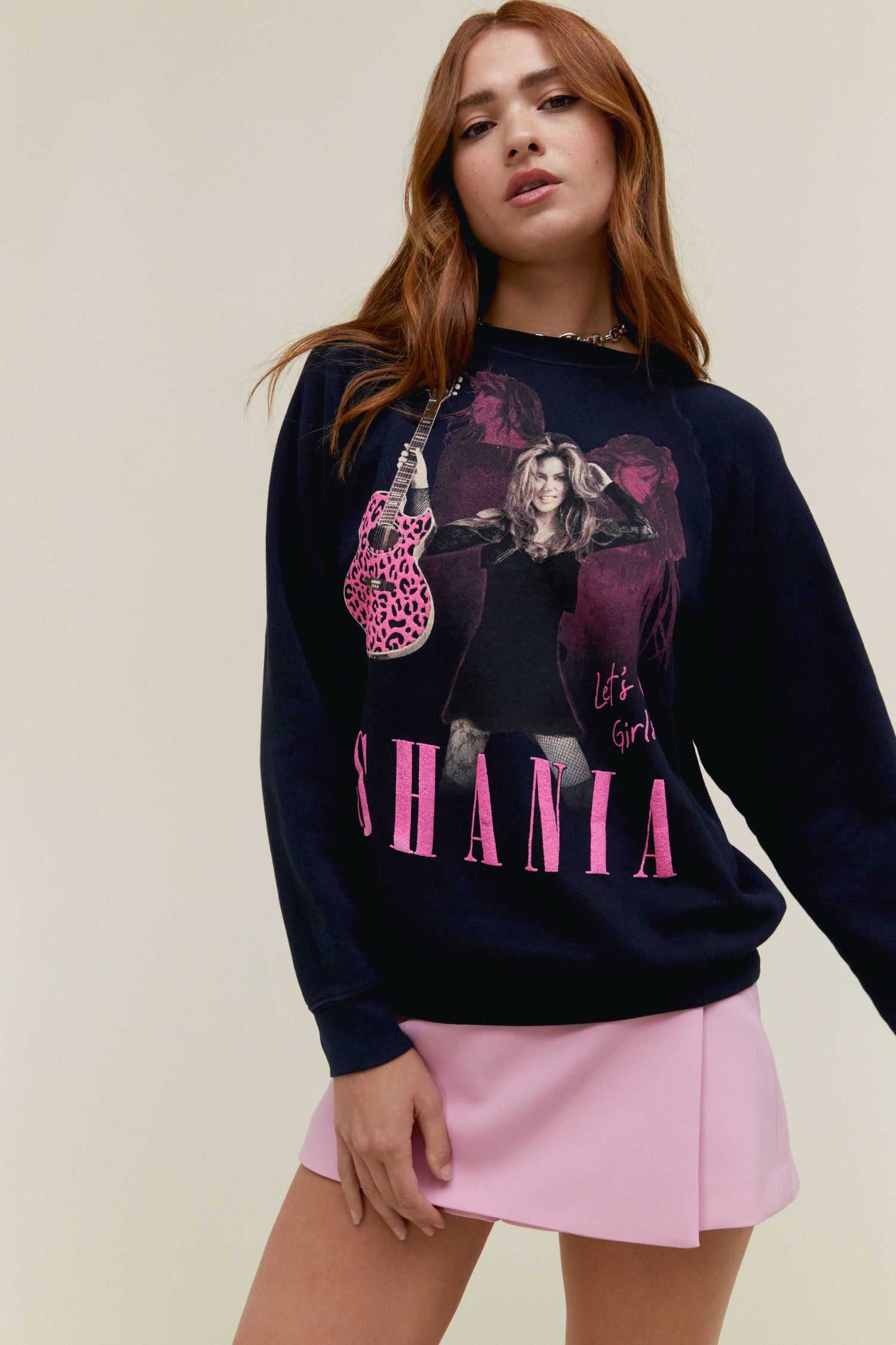 A model featuring a black sweatshirt stamped with "SHANIA" and a portrait of the artist holding a guitar.