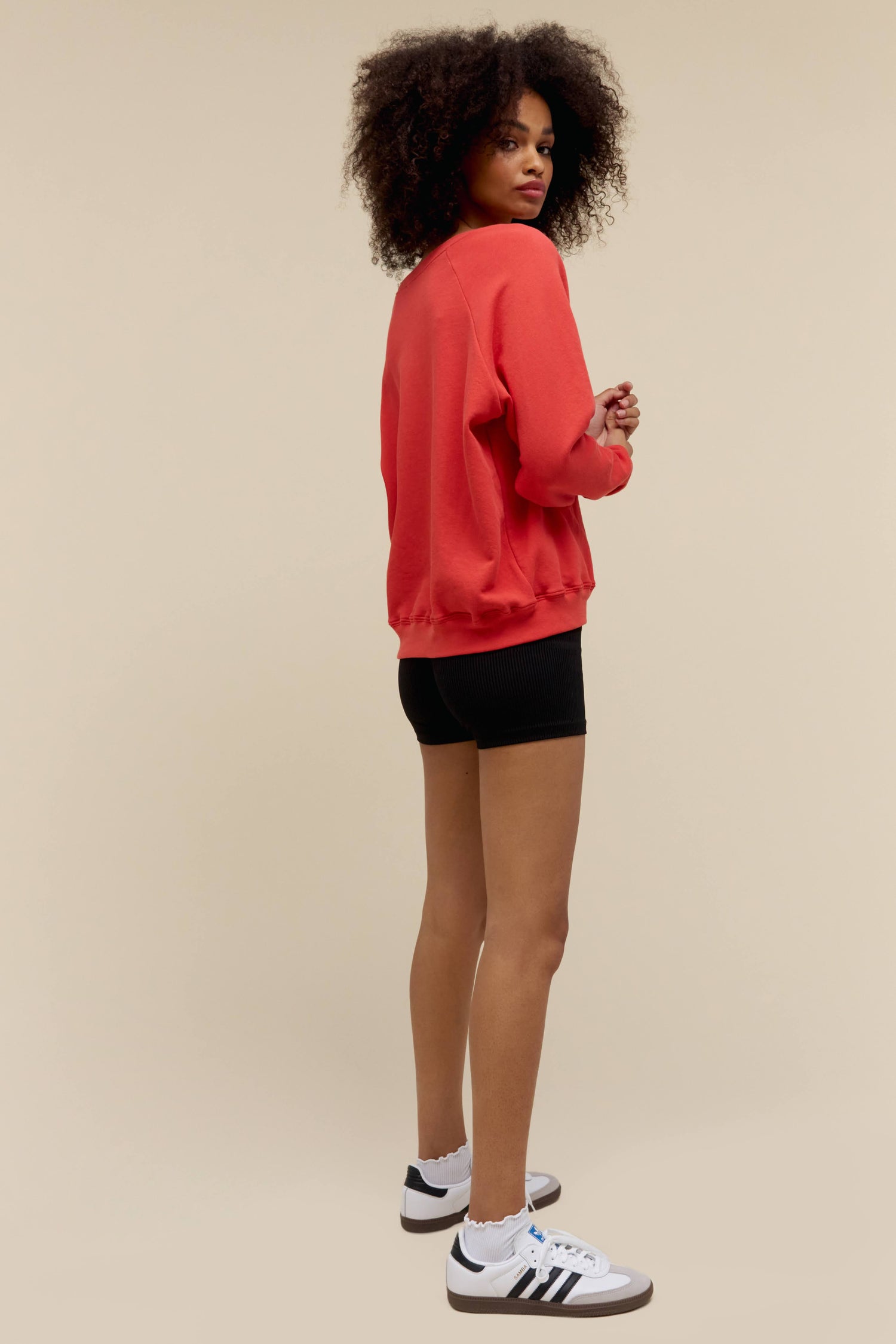 A model featuring a red raglan sweatshirt stamped with Daydreamer in the middle.