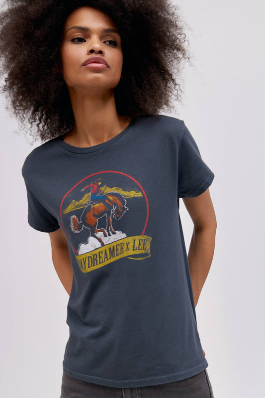 A curly-haired model featuring a black tour tee designed with a fresh rendition of a tried and true Lee vintage rodeo graphic hits a relaxed fit, Tour Tee.