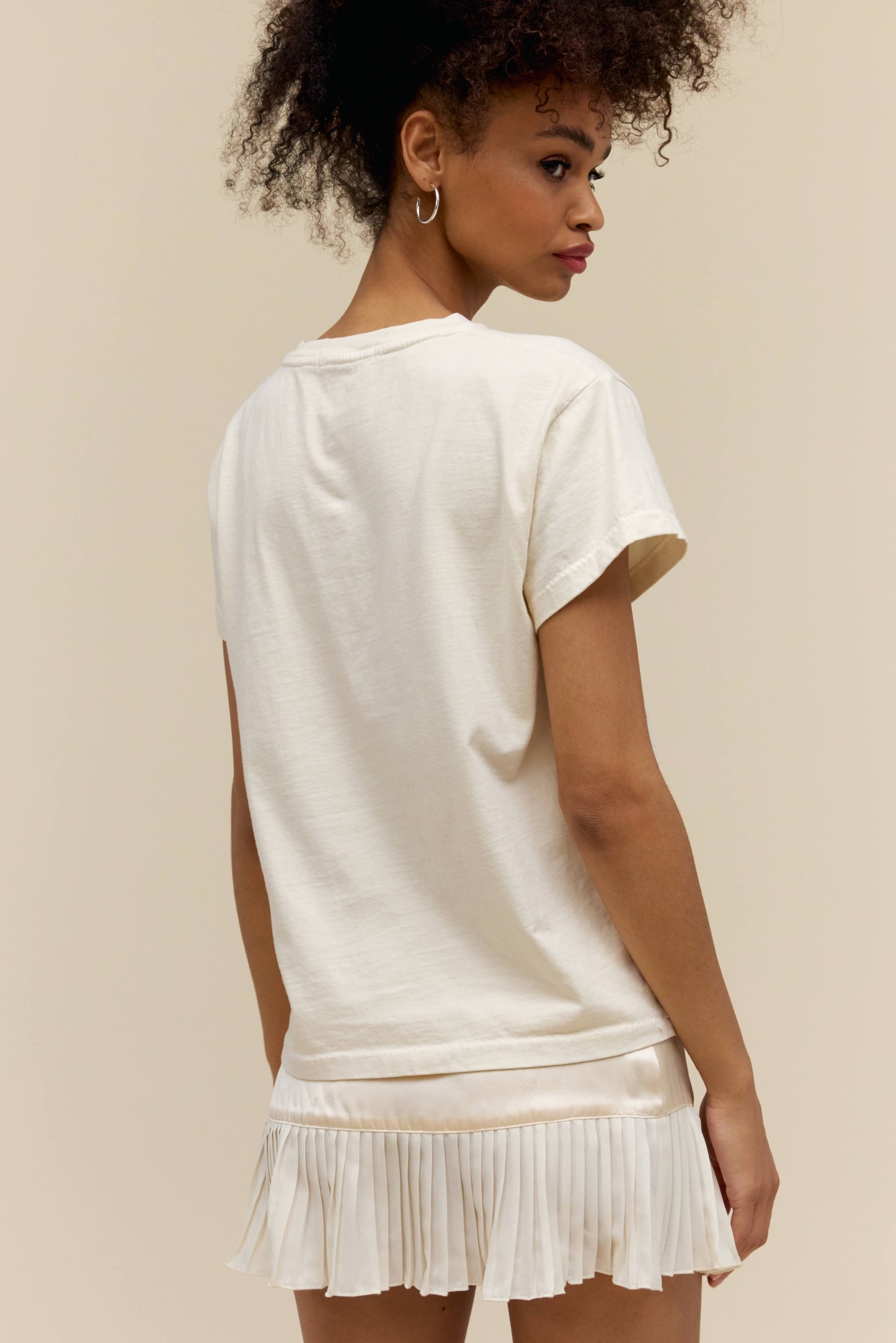 A model featuring a white tee stamped with 'Neil Young' and a graphic of a beach.