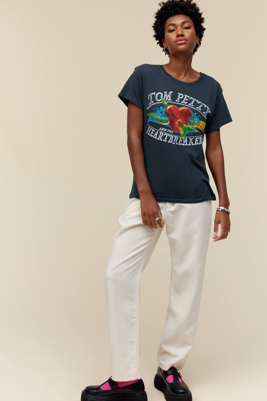 A model featuring a black tee stamped with Tom Petty and designed with a graphic heart on the center.