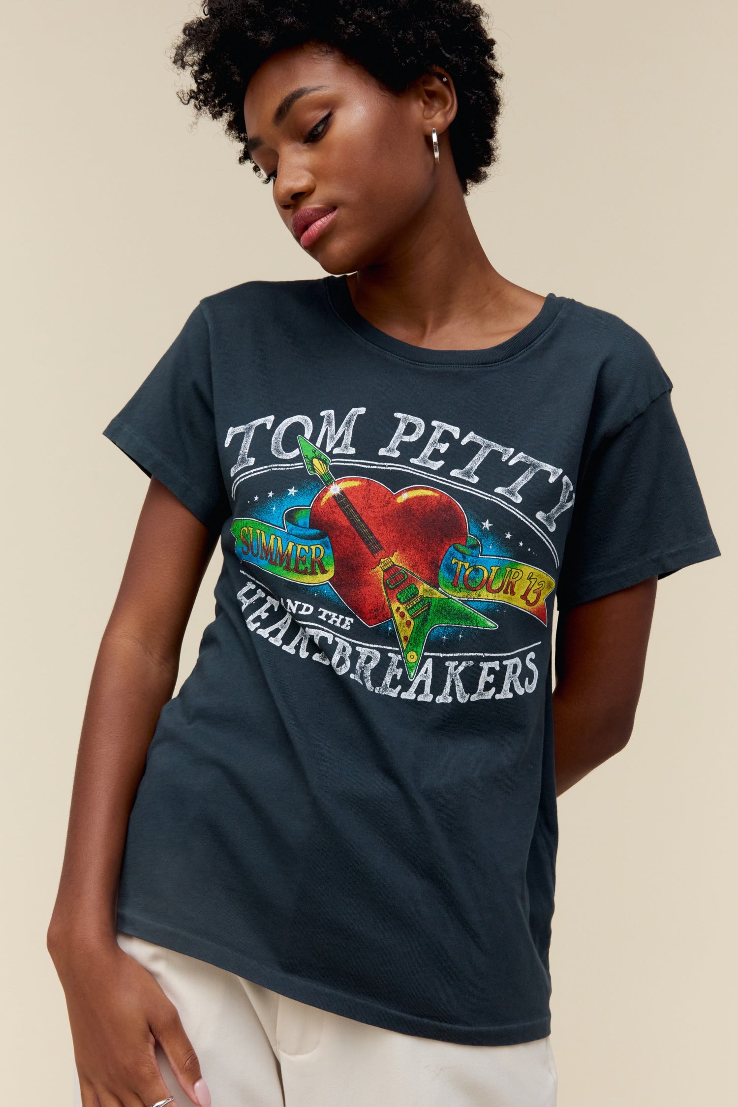 A model featuring a black tee stamped with Tom Petty and designed with a graphic heart on the center.